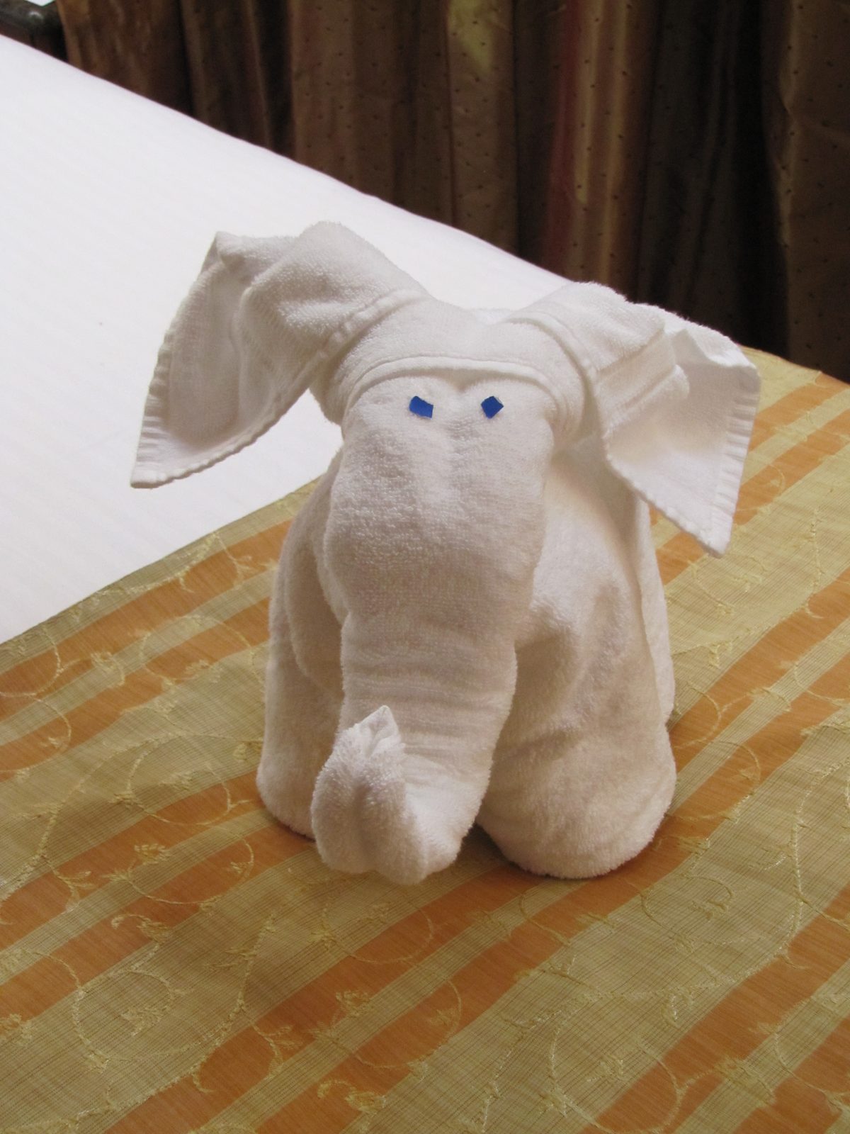 A towel elephant waiting on the bed