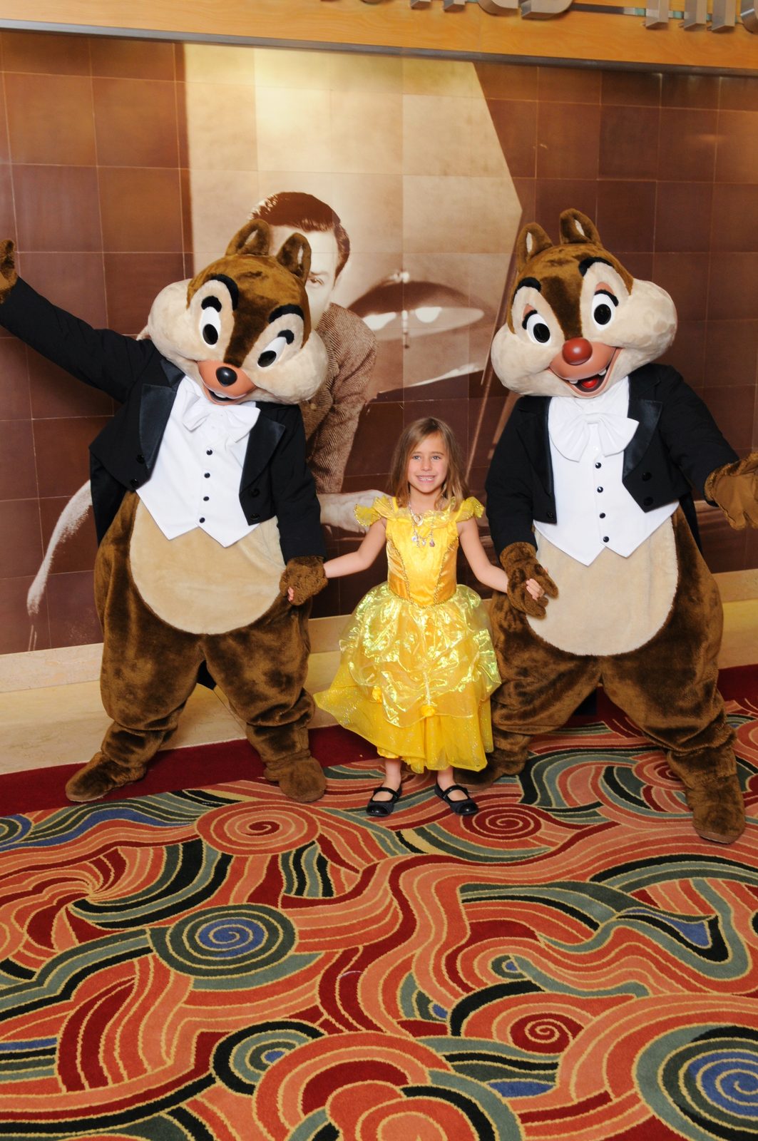 Lisa in her Belle dress between Chip and Dale in their tuxedos in the Lobby Atrium