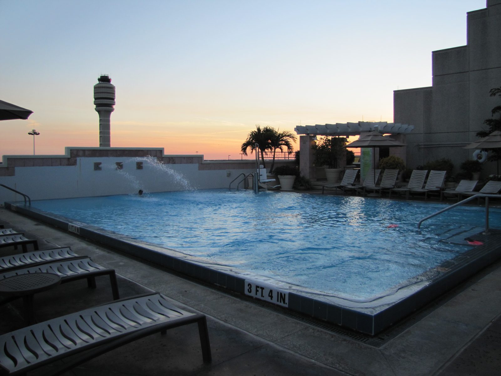 Pool and palm trees with the control tower behind, evening before boarding