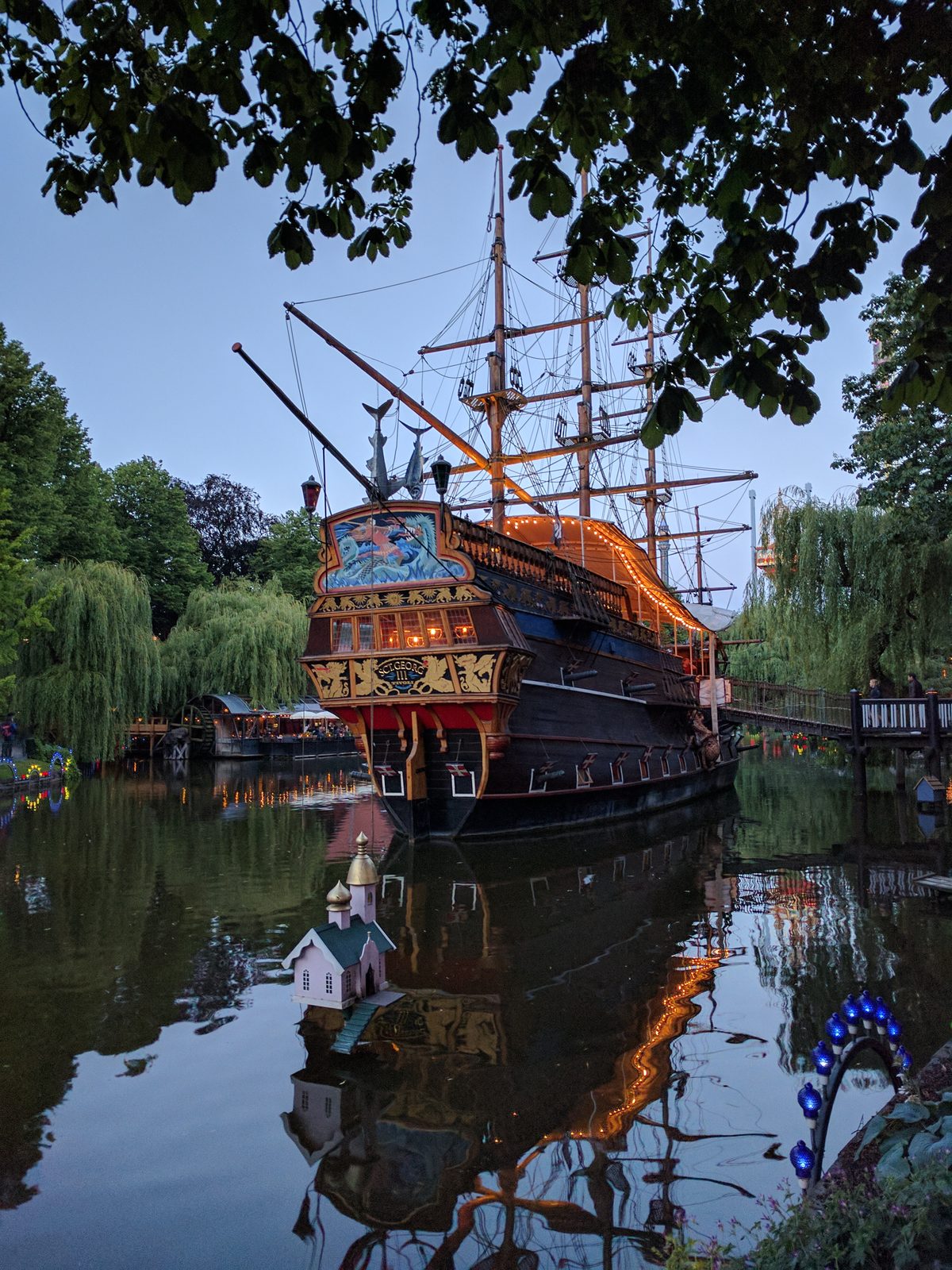 The pirate ship glowing on the water at dusk