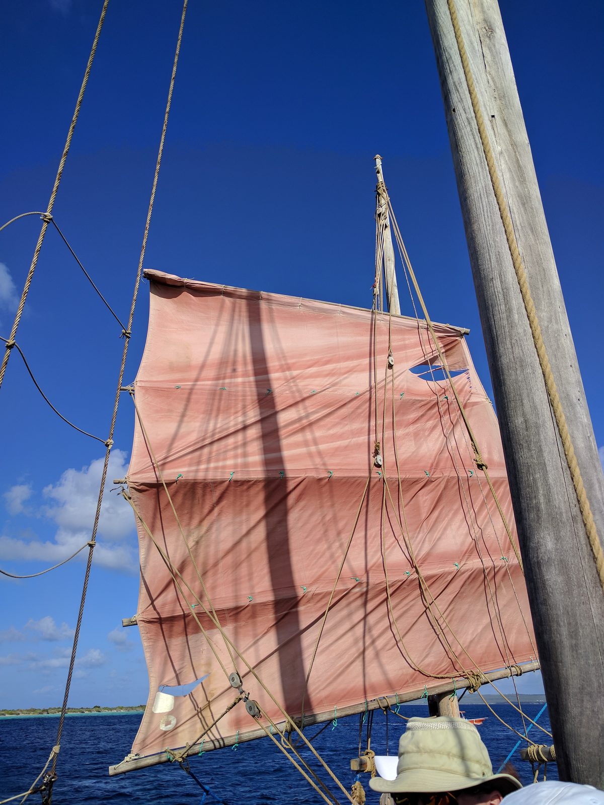 The sailboat's orange sail against the sky