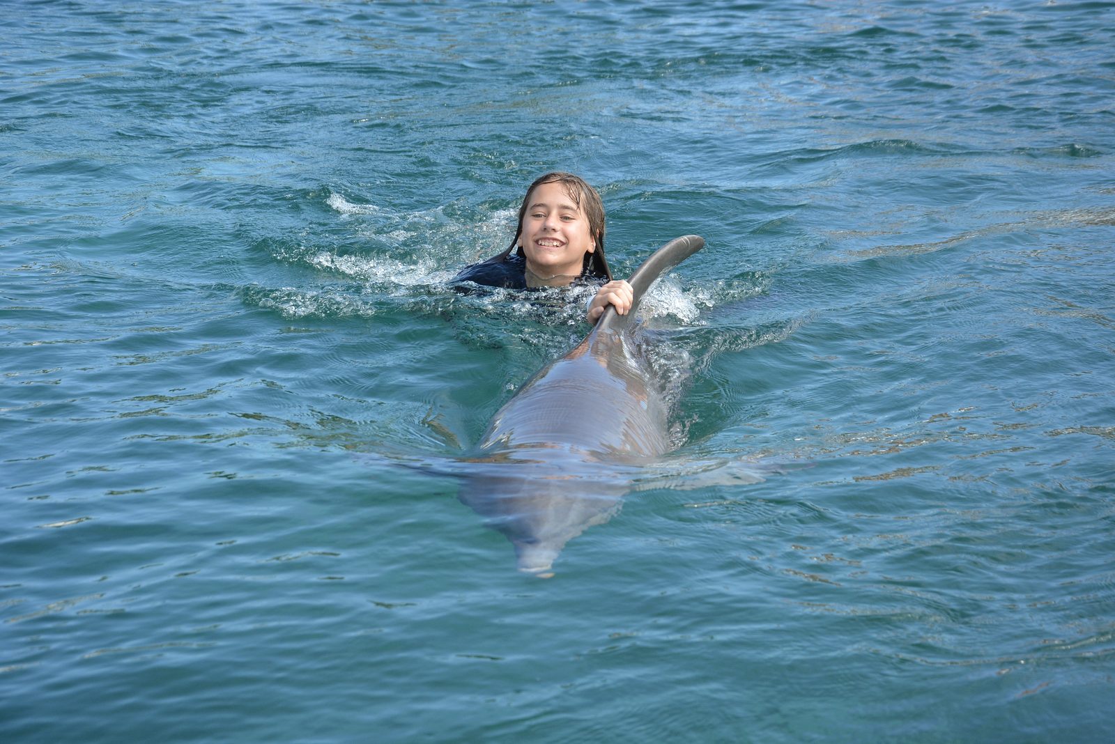 Lisa riding along with the dolphin at Dolphin Cay