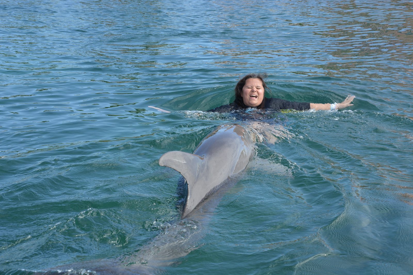 Kathy floating on her back with the dolphin at Dolphin Cay