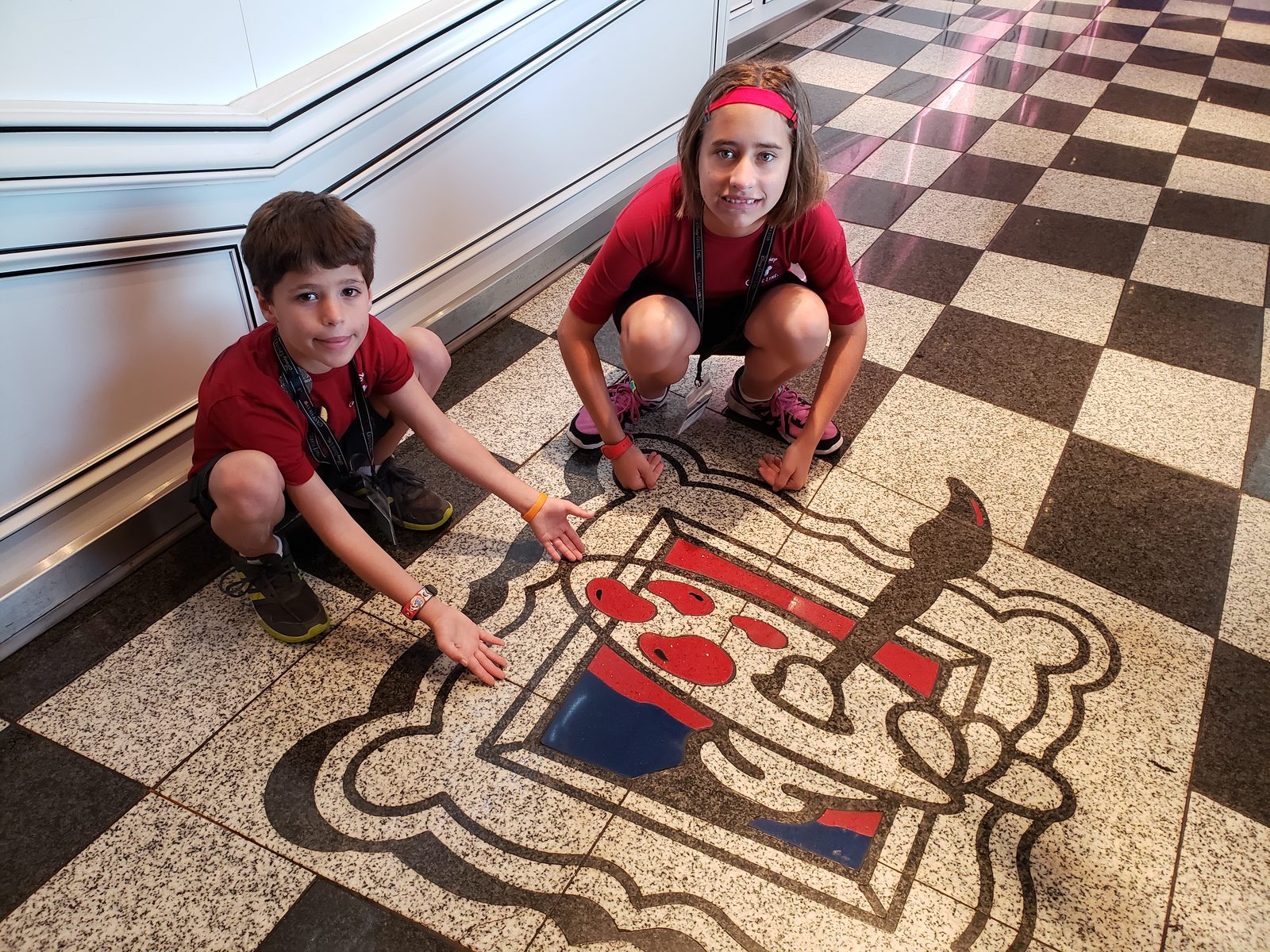 The kids crouched over the lobby floor medallion
