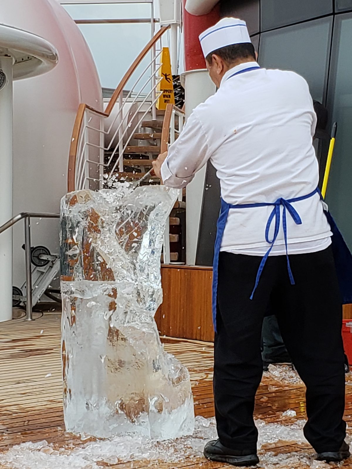 A chef carving an ice sculpture on the pool deck
