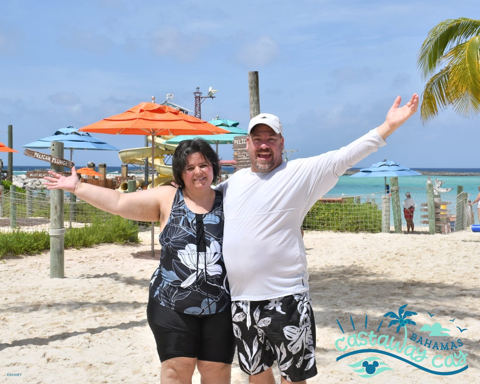 Kathy and Michael with arms wide on the beach at Castaway Cay