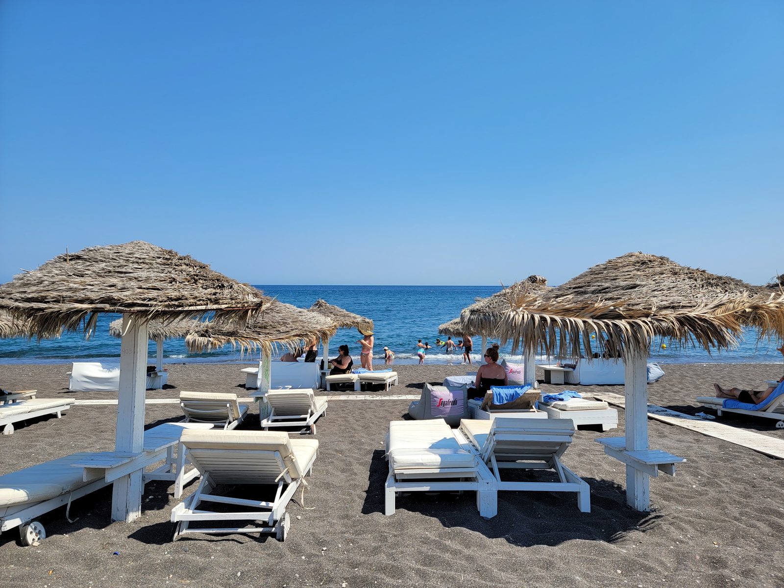 Thatched umbrellas on the black sand at Perivolos