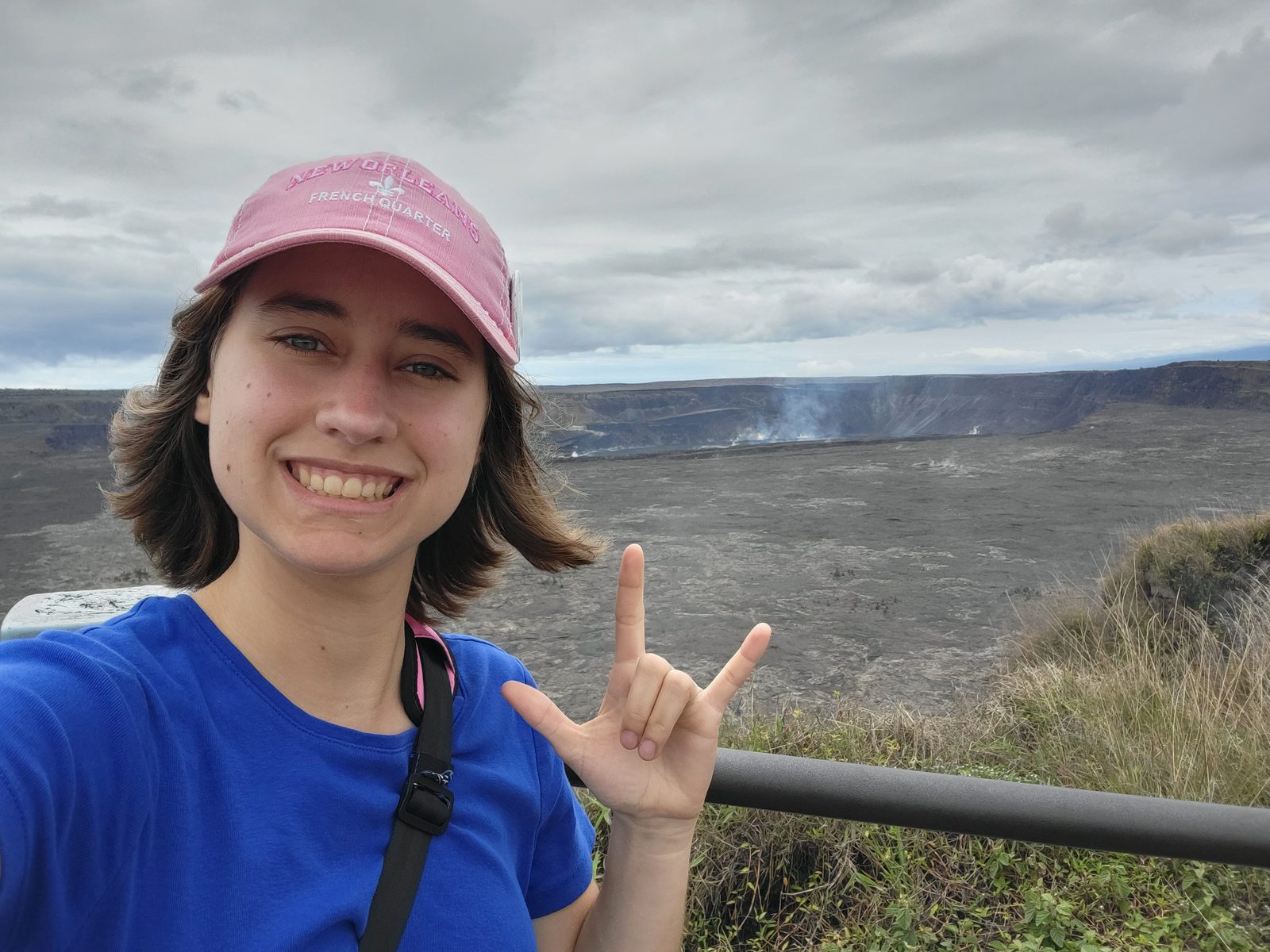 Lisa signs I love you with the volcano behind her