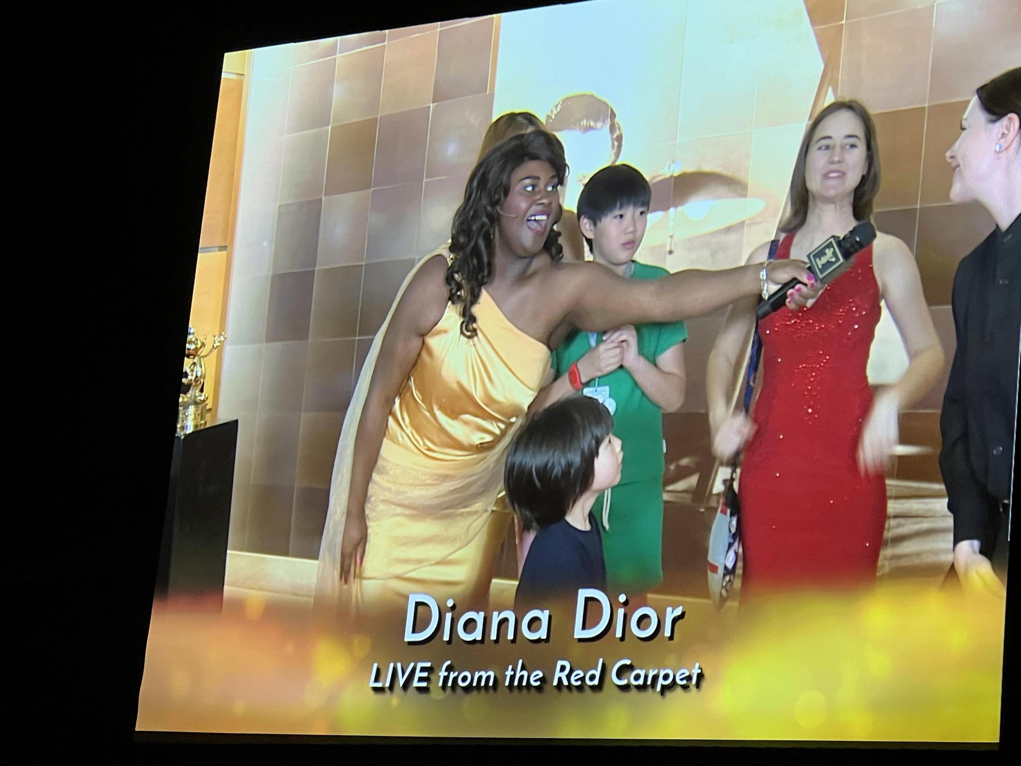Diana Dior live from the Golden Mickeys red carpet on screen interviewing Lisa, with Erika interpreting