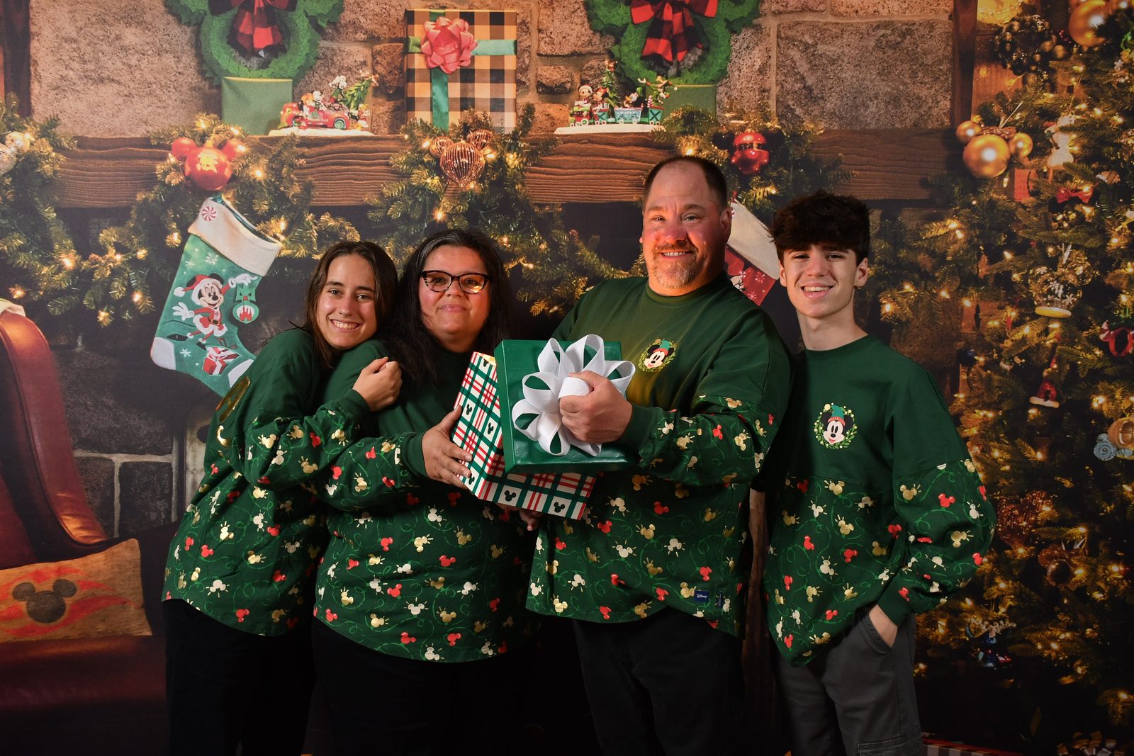 Lisa, Kathy, Michael and Thomas in matching Christmas sweaters by the fireplace