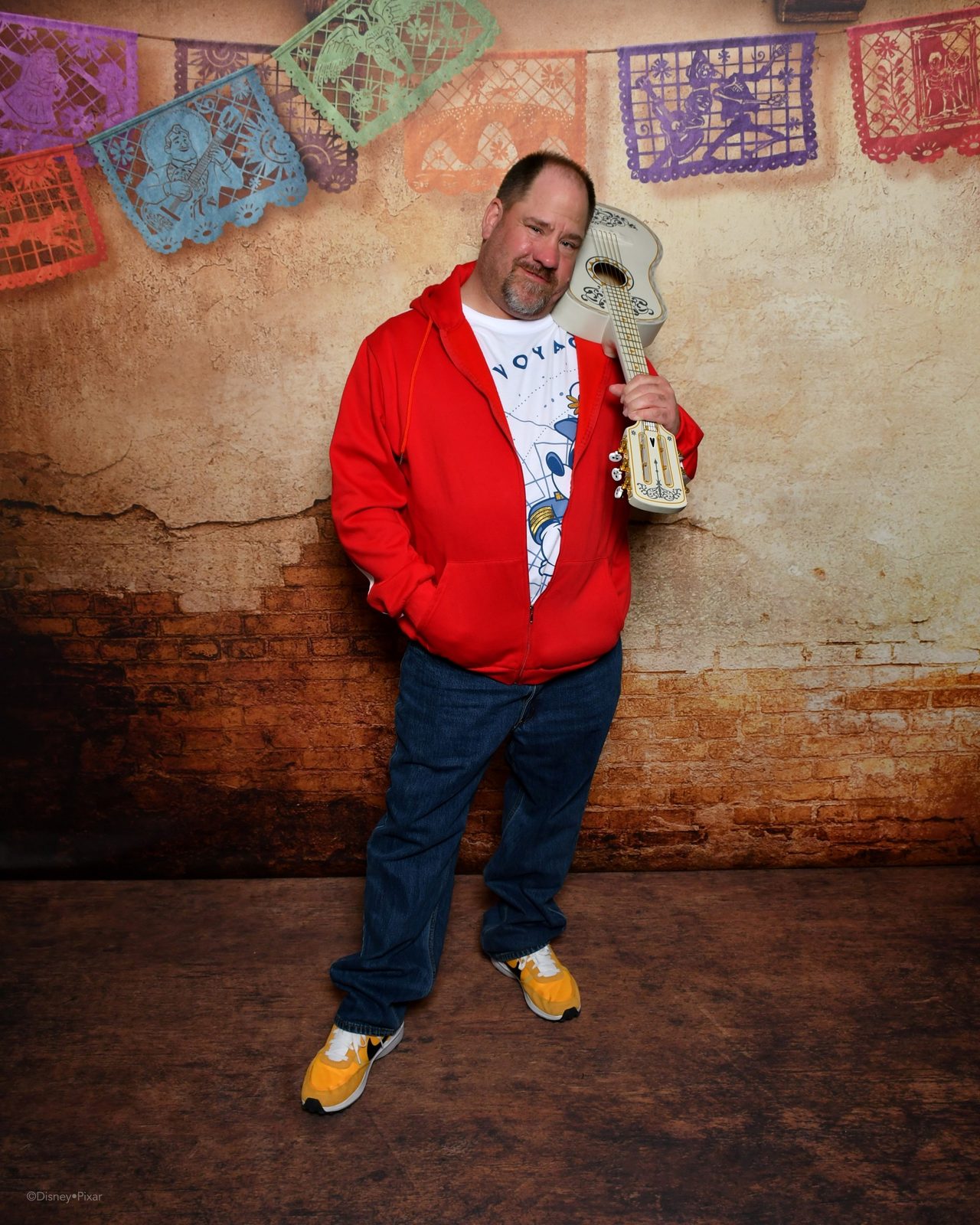 Michael with a guitar at the Coco backdrop on the Treasure