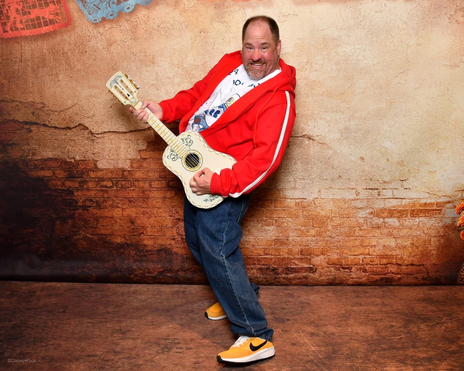 Michael with a guitar at the Coco backdrop on the Treasure