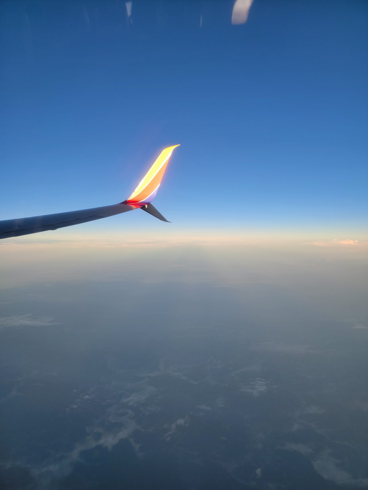 The wing catching first light over the clouds