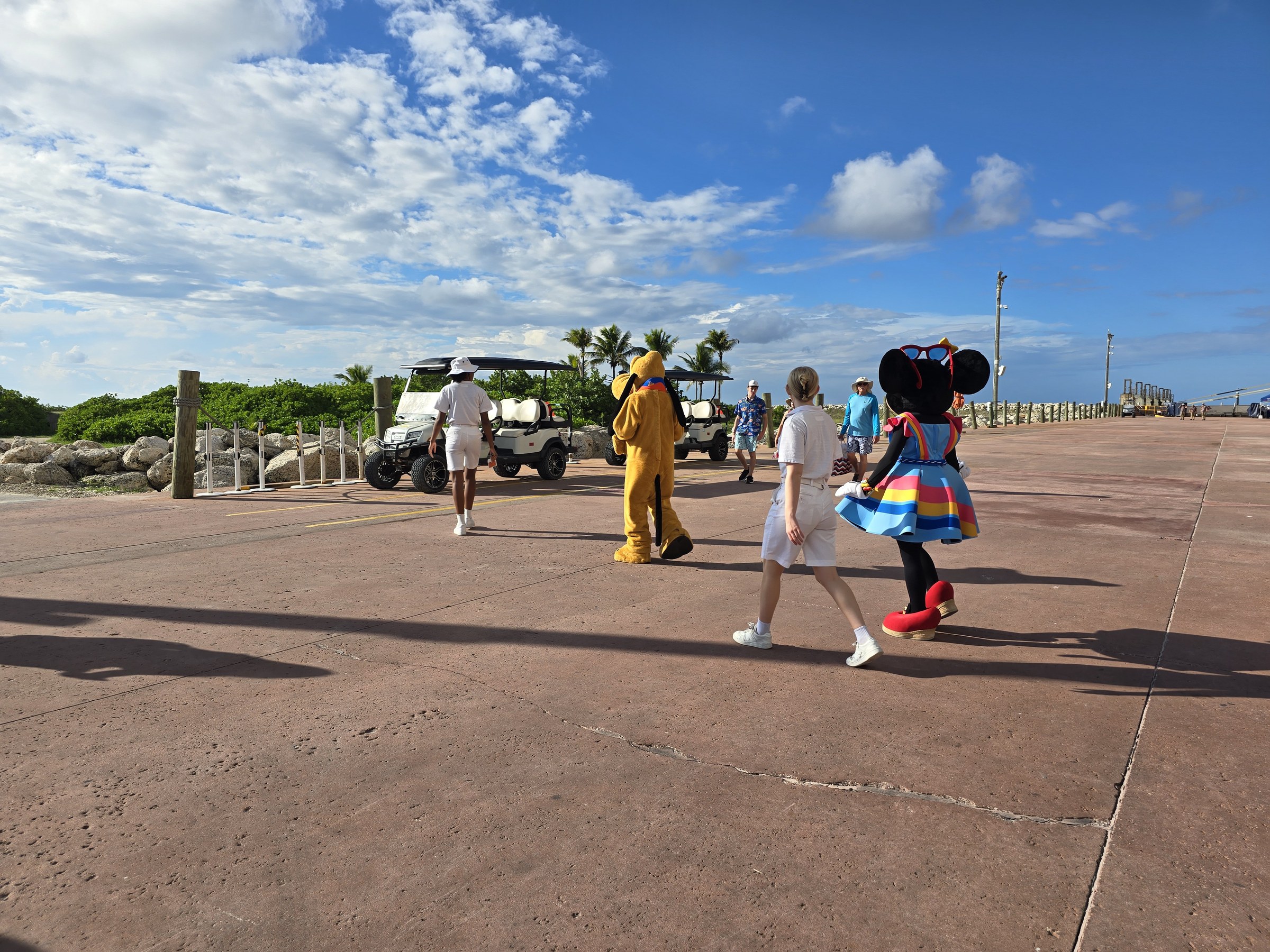 Minnie in her Castaway Cay outfit and Pluto heading up the pier