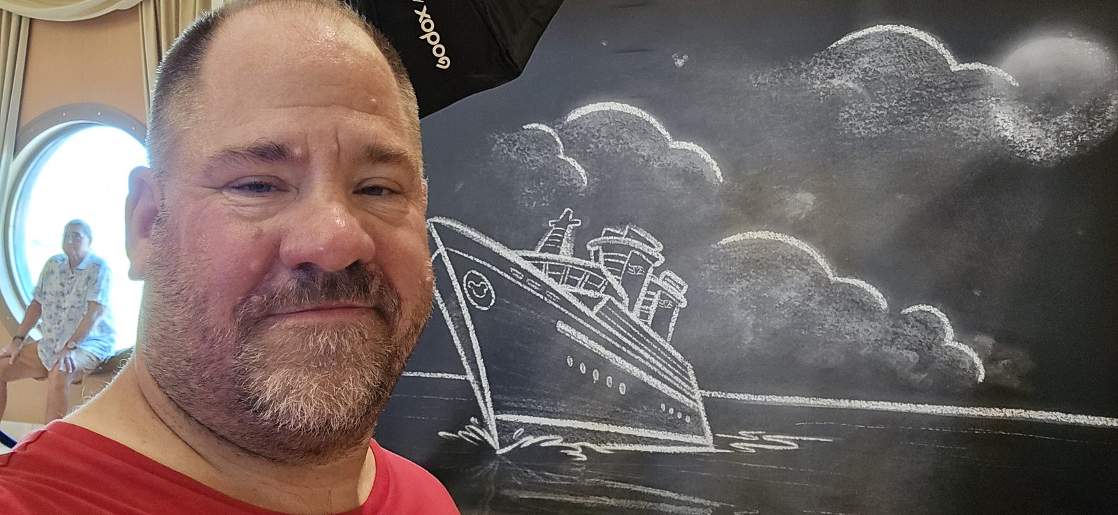 Michael beside a chalkboard ship drawing