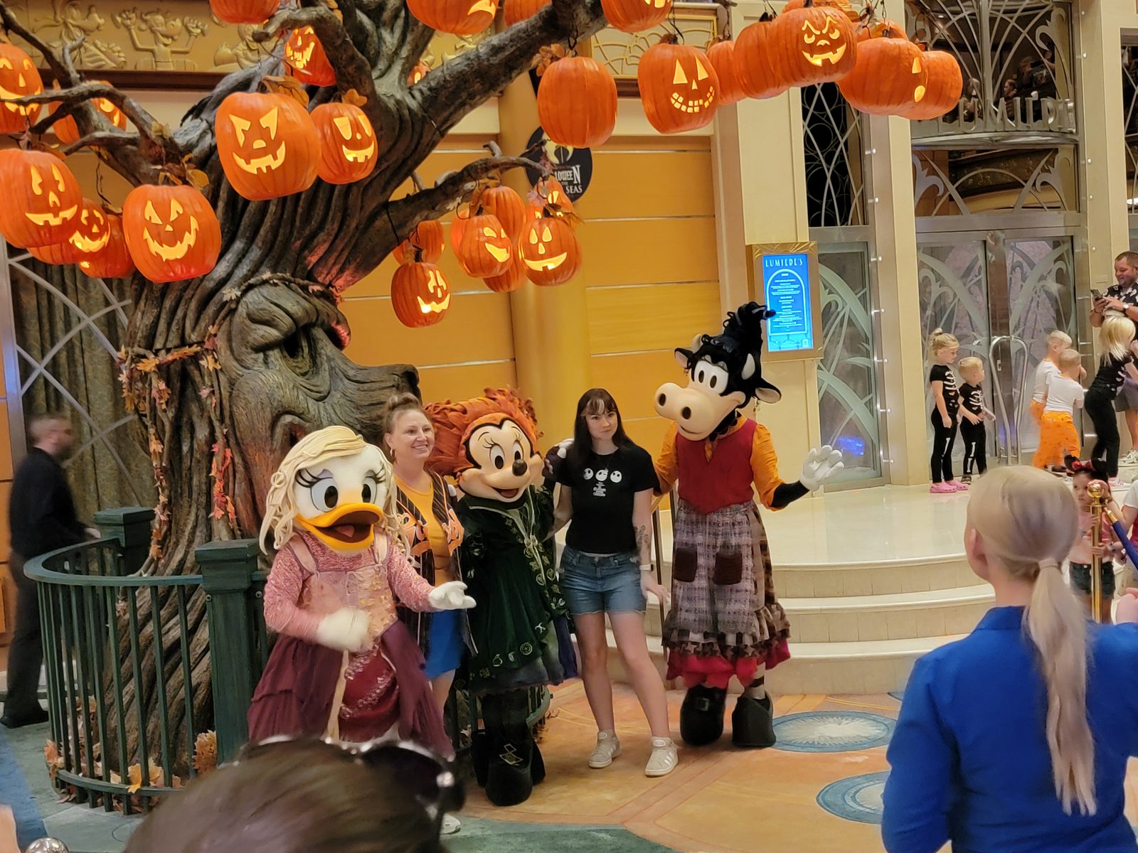 Daisy, Minnie & Clarabelle in their Sanderson Sisters Halloween costumes under Reap the Pumpkin Tree