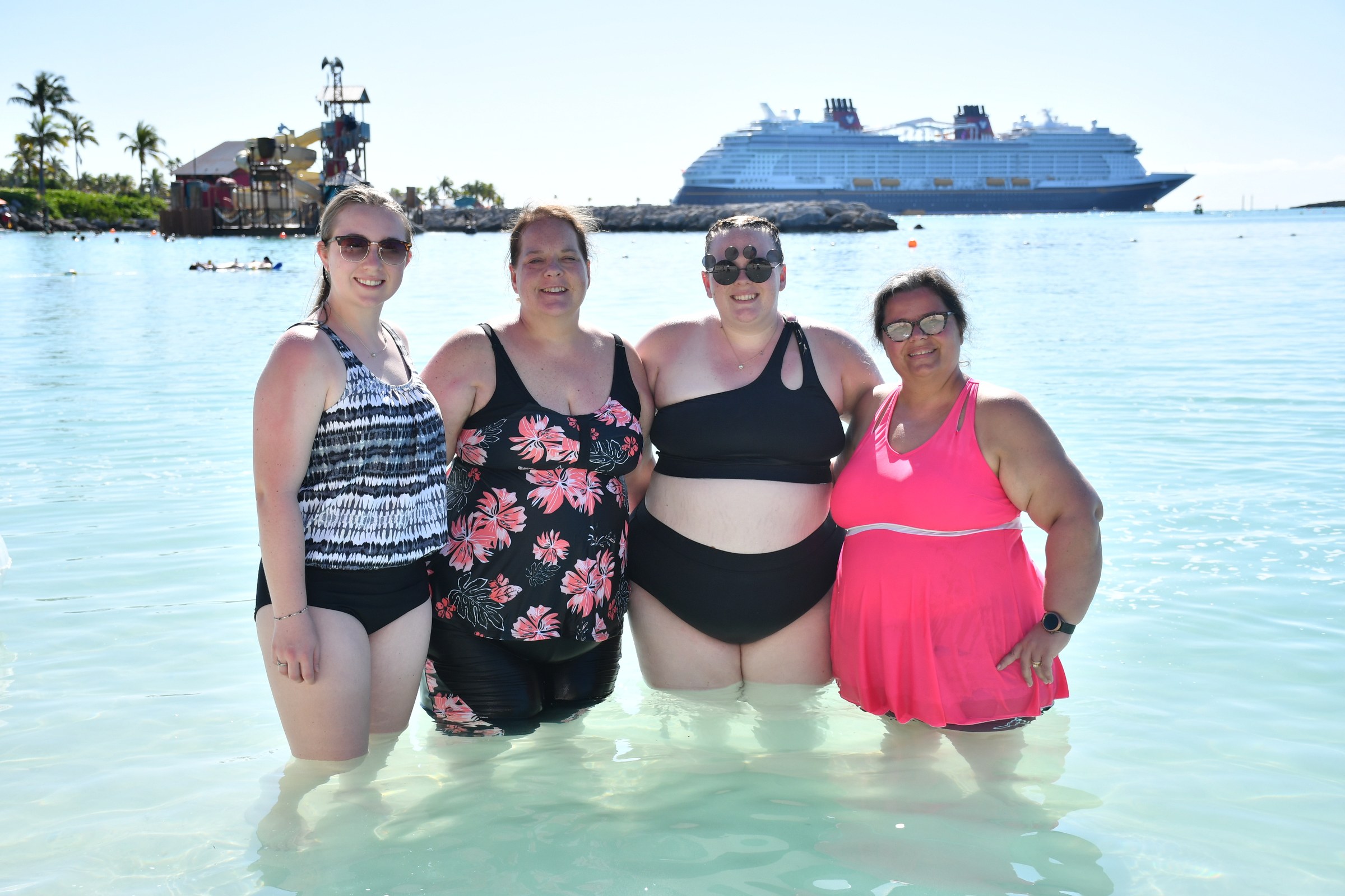 Krissy and Kathy with friends at Castaway Cay, the ship behind them