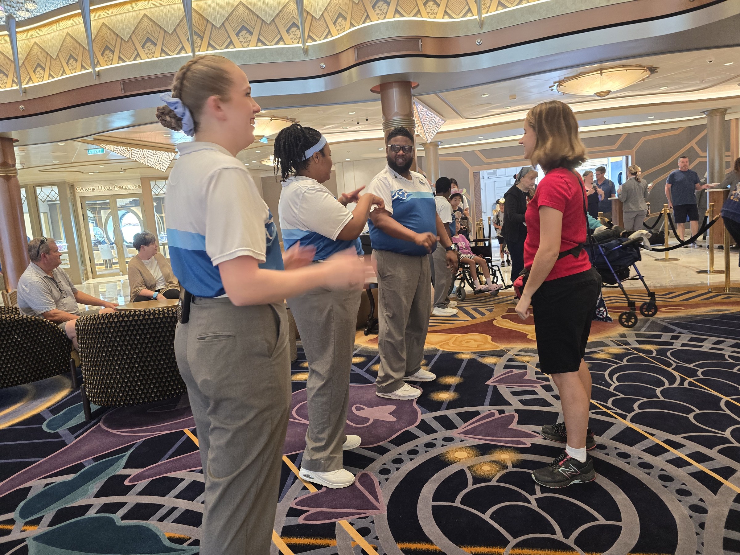 Dominique, second from the left, and two more Cast Members with Lisa in the Grand Hall on boarding day