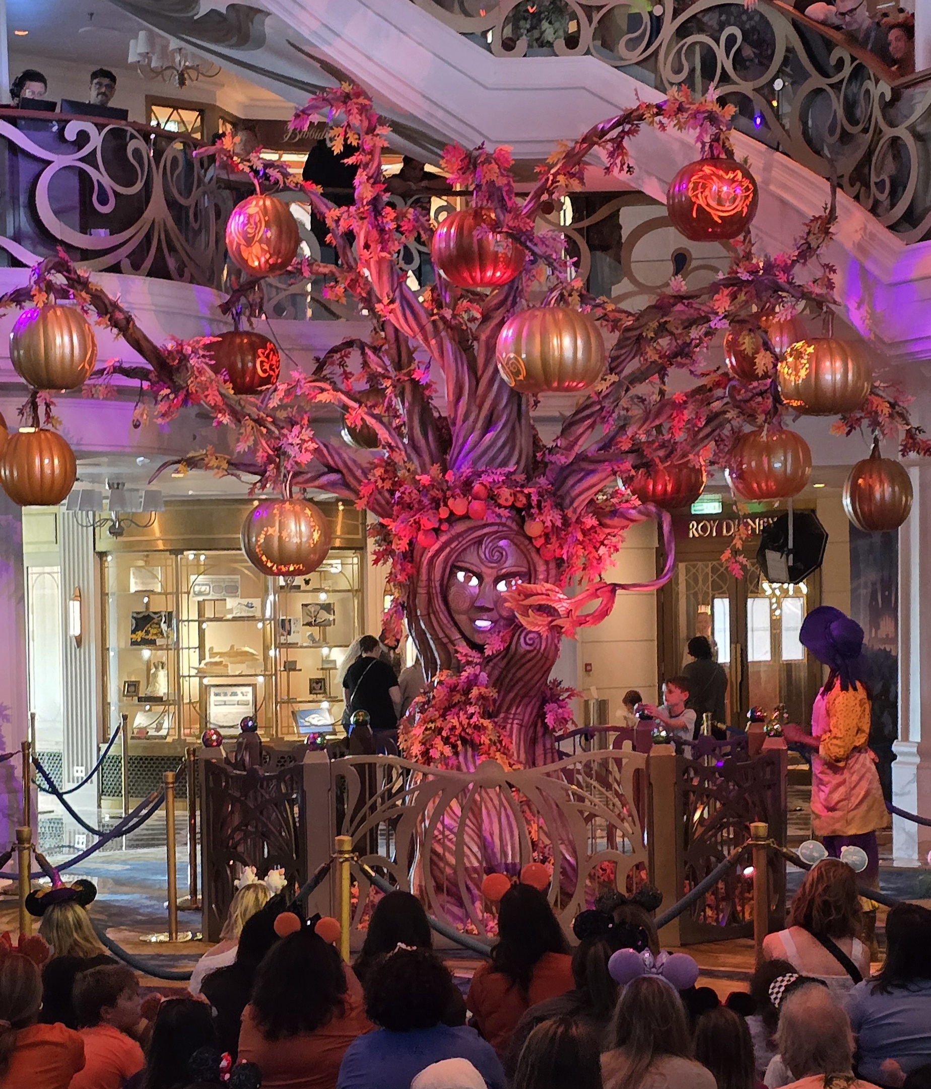 Boo the Pumpkin Tree lit up in the Grand Hall as guests gather around