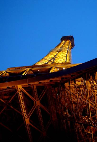 Under the Eiffel Tower's ironwork at night