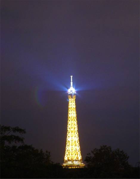 The Eiffel Tower's beacon sweeping the night sky