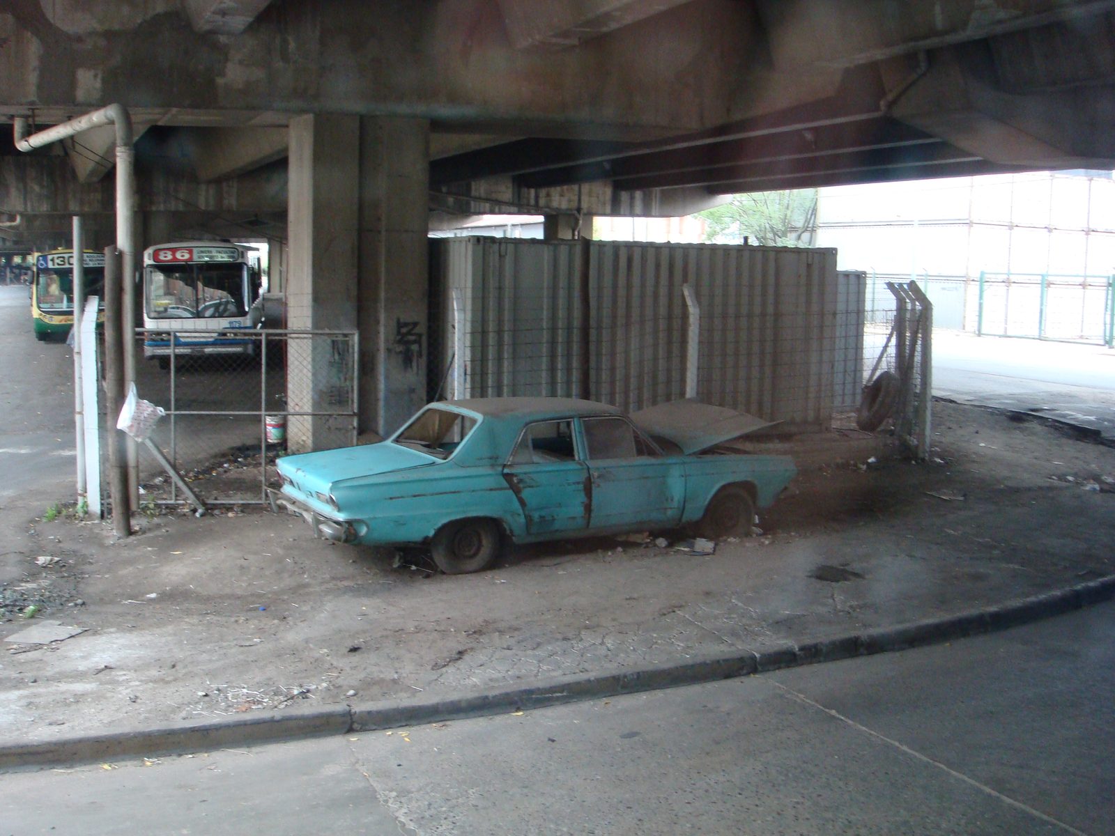 An old blue car parked under the bridge in La Boca