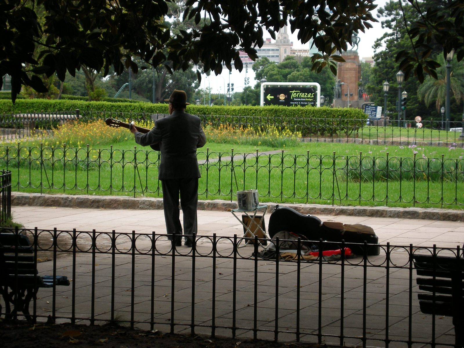 A street musician playing guitar along the fence