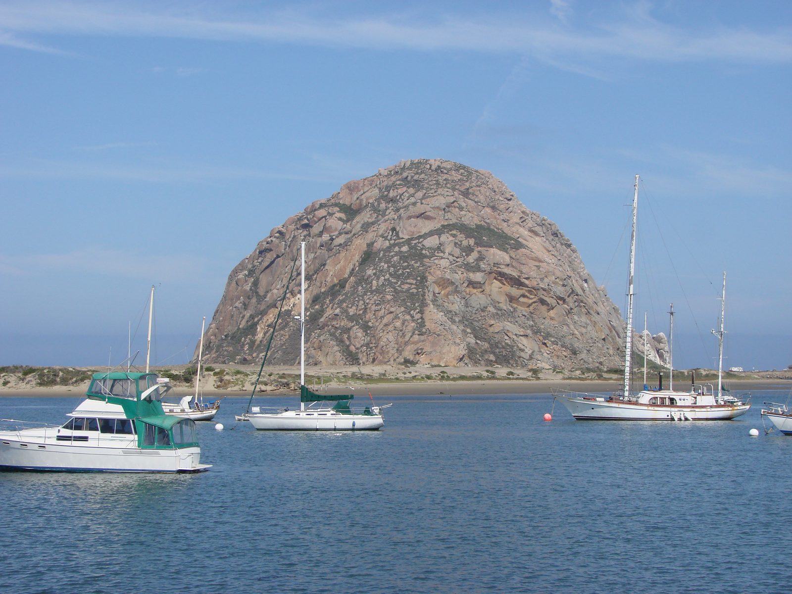 Sailboats at anchor below a rocky dome on the coast
