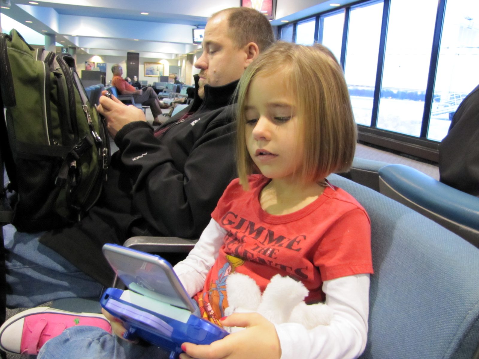 Lisa and her handheld game, with Michael at the Detroit gate