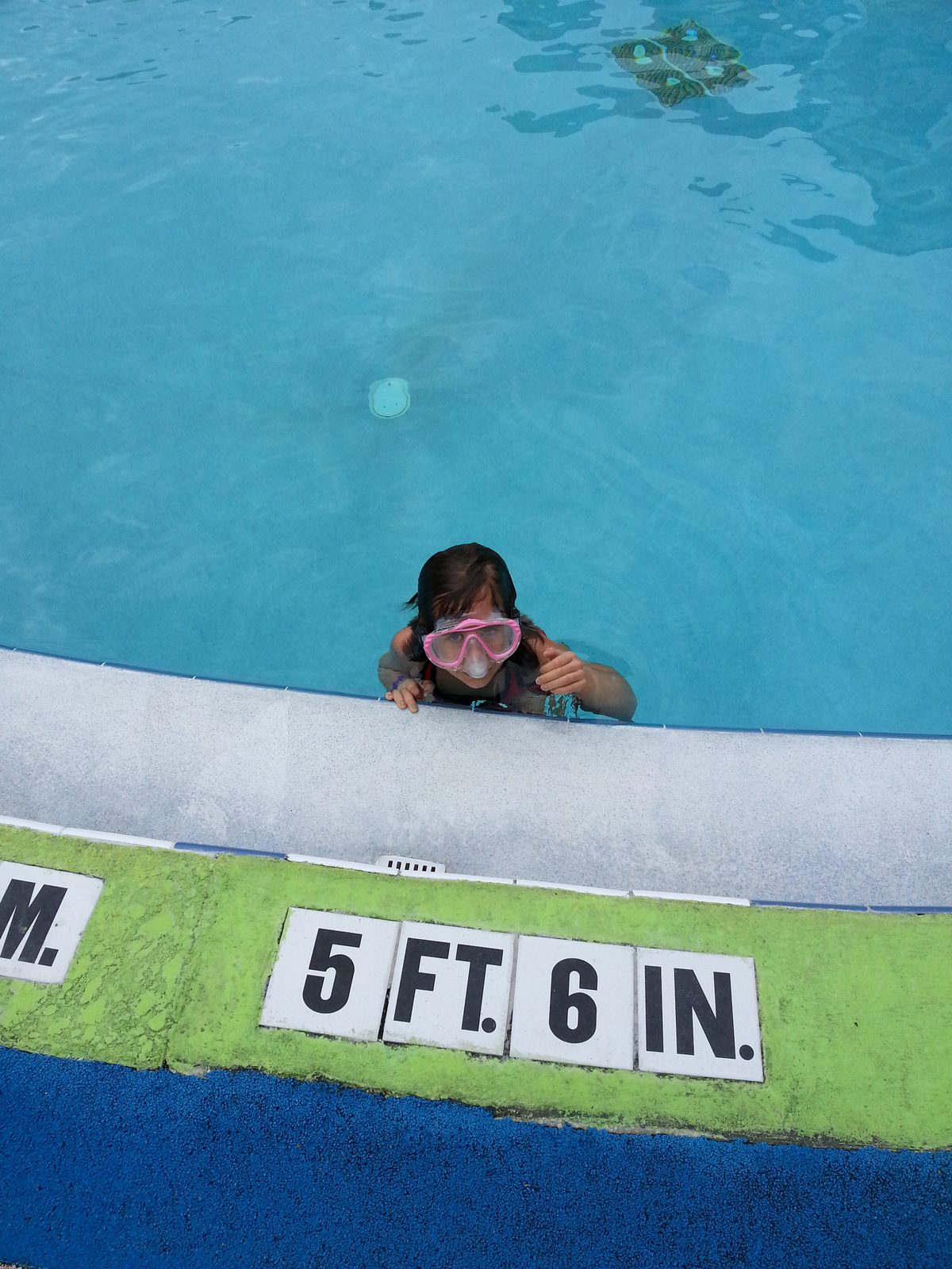 Lisa peeks over the pool's edge at the depth marker