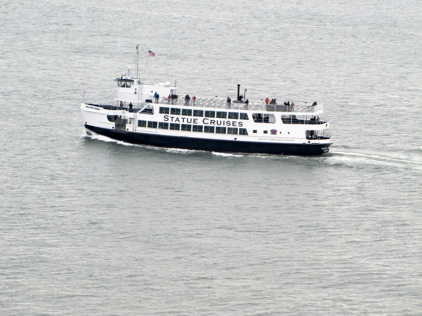 A Statue Cruises ferry crossing the grey harbor beneath us