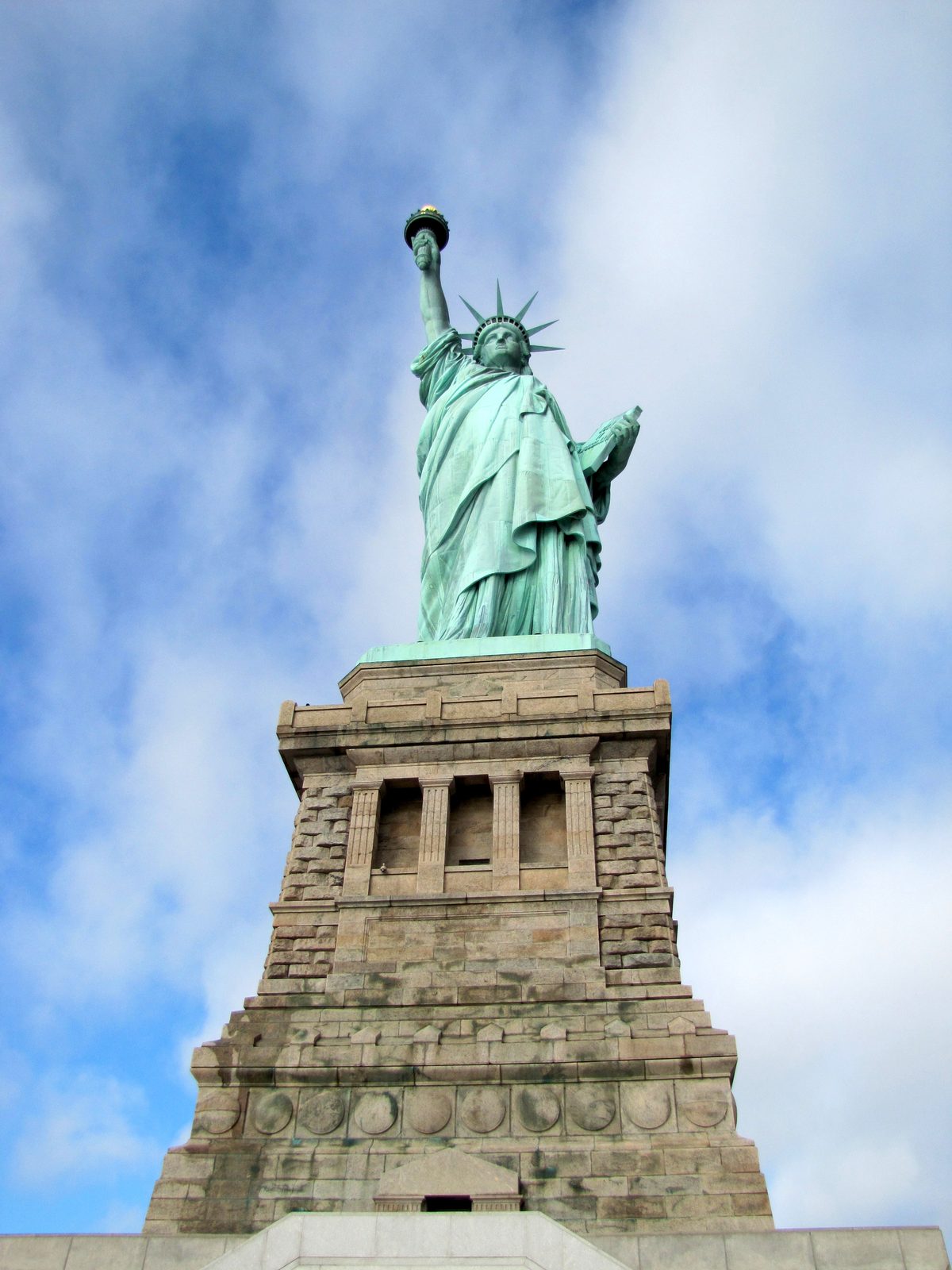 The Statue of Liberty rising over her pedestal under a bright blue sky