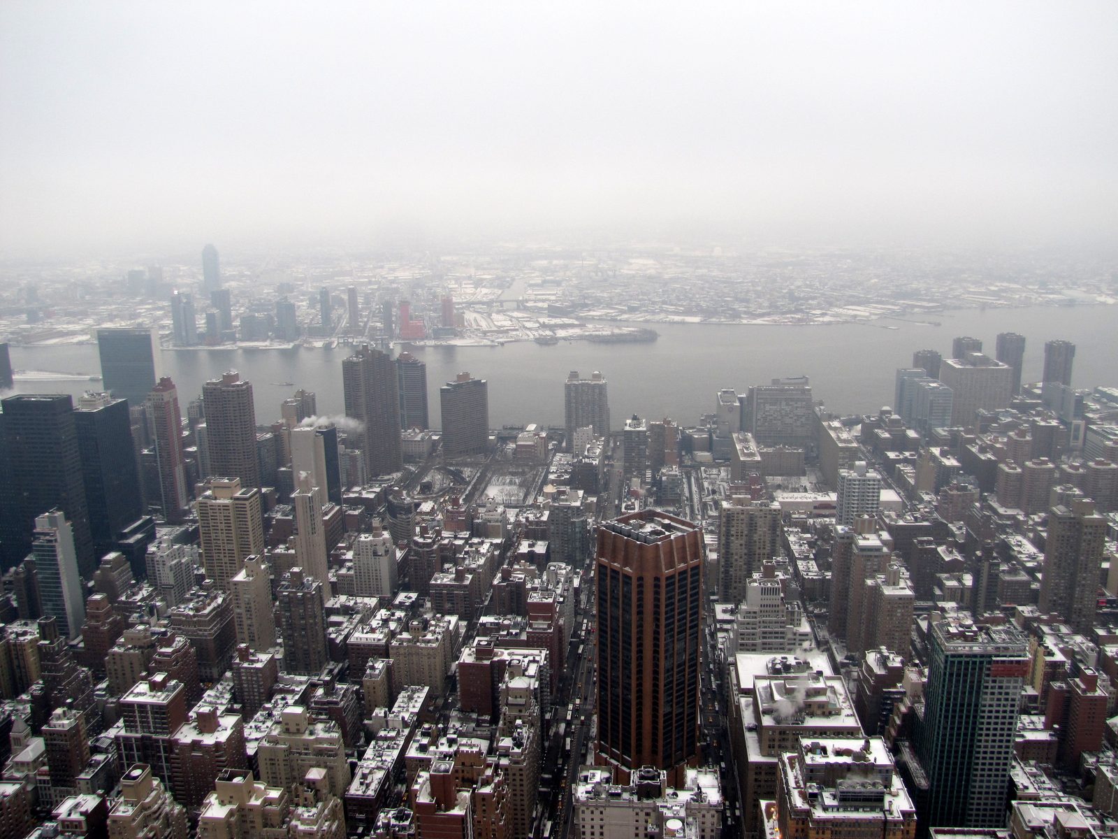 Snowy Manhattan rooftops and the river from high above the city