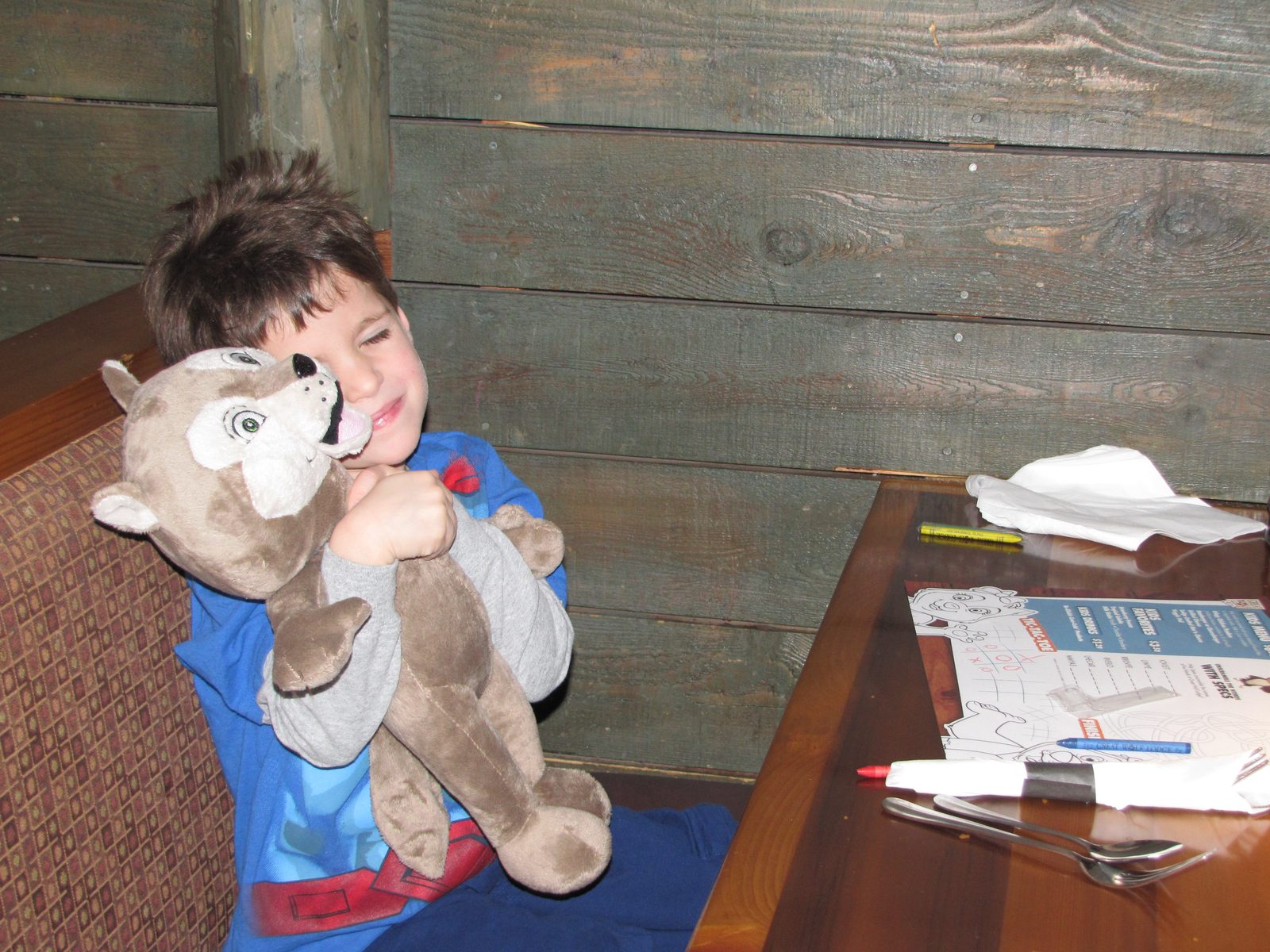 Thomas hugs his new stuffed wolf at dinner