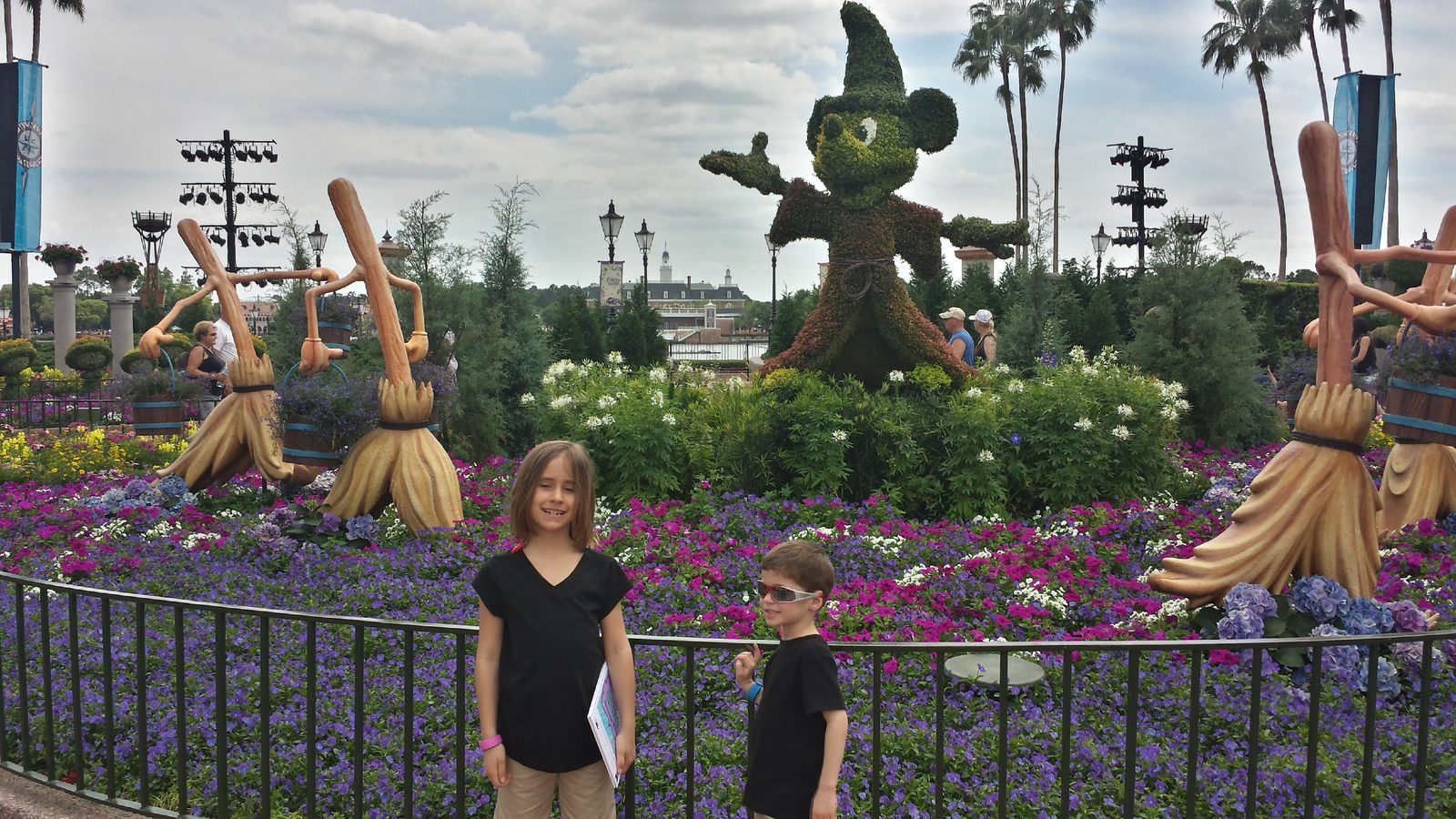 The kids by the Sorcerer Mickey topiary at Epcot