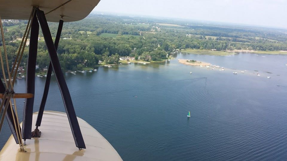 A lake below the wing of the biplane