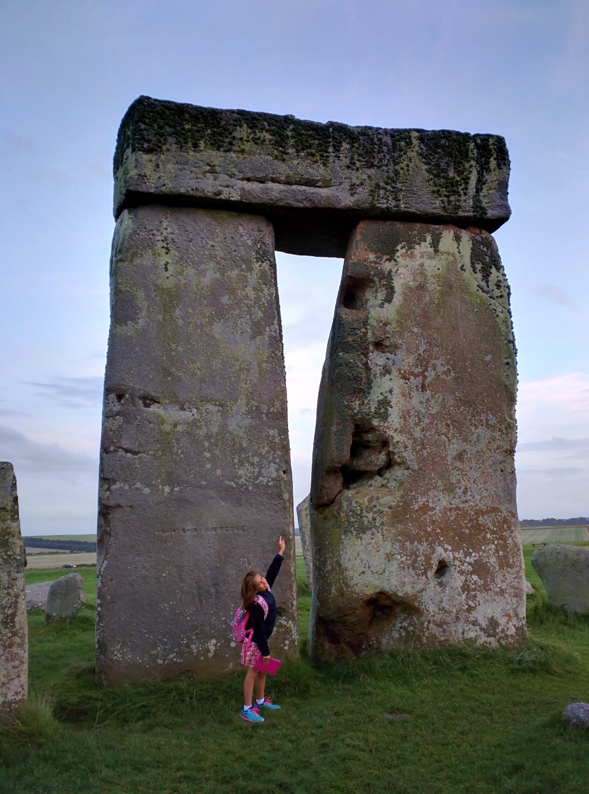 Reaching up to touch a stone at Stonehenge