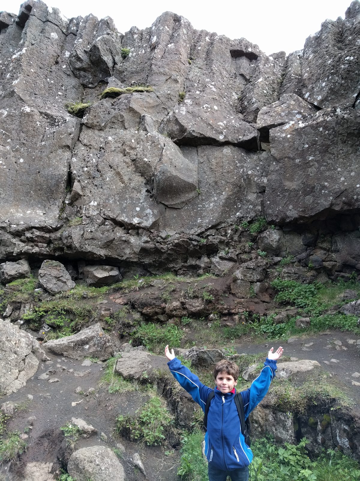 Thomas with his arms up between the rock walls at Þingvellir
