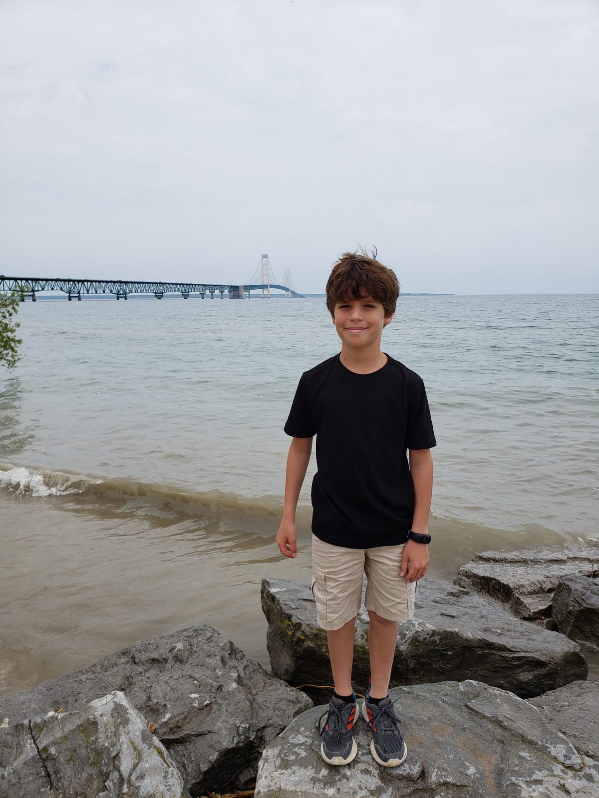 Thomas on the shoreline rocks, Mackinac Bridge behind