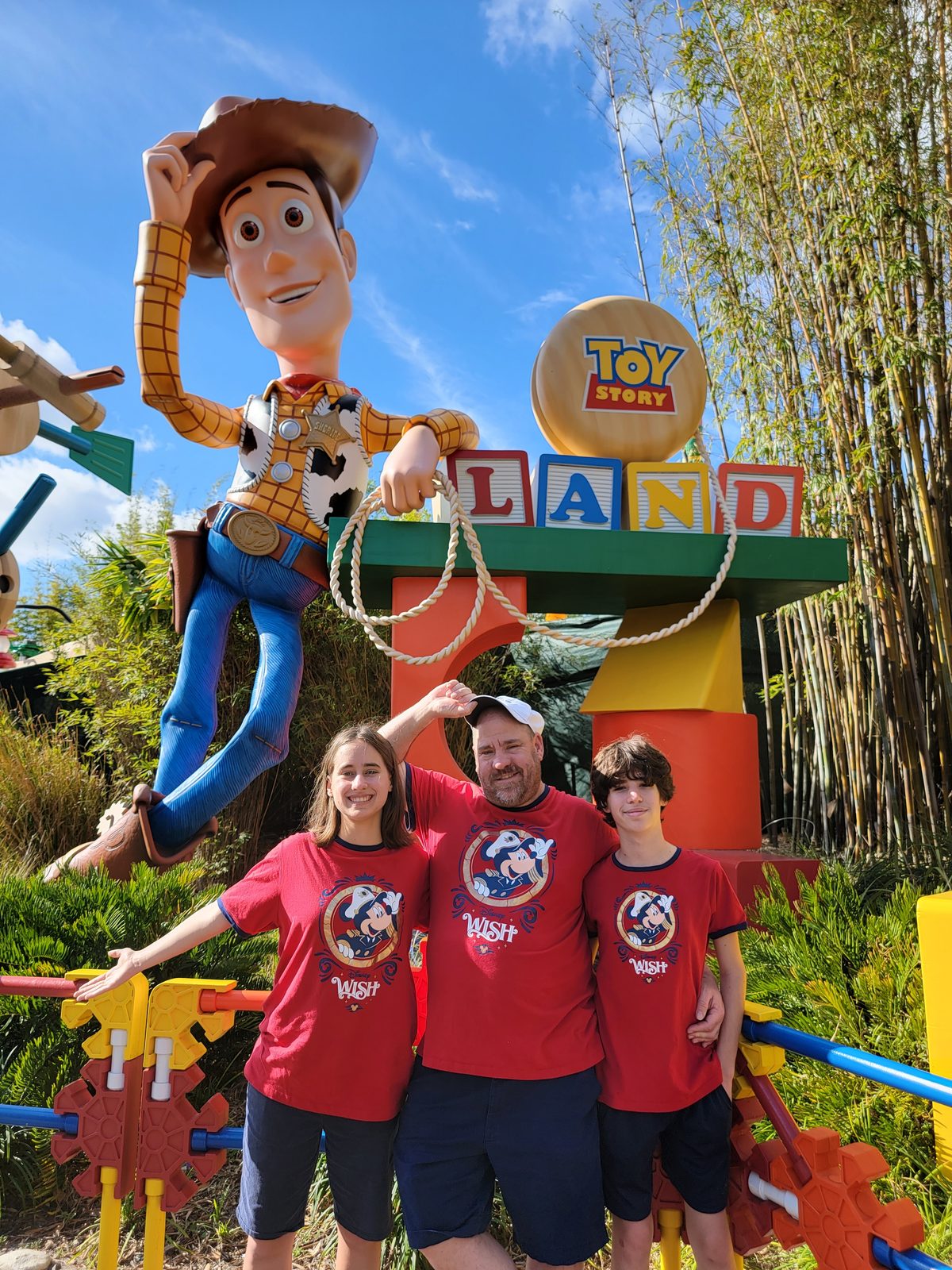 Lisa, Michael and Thomas under Woody at the Toy Story Land sign