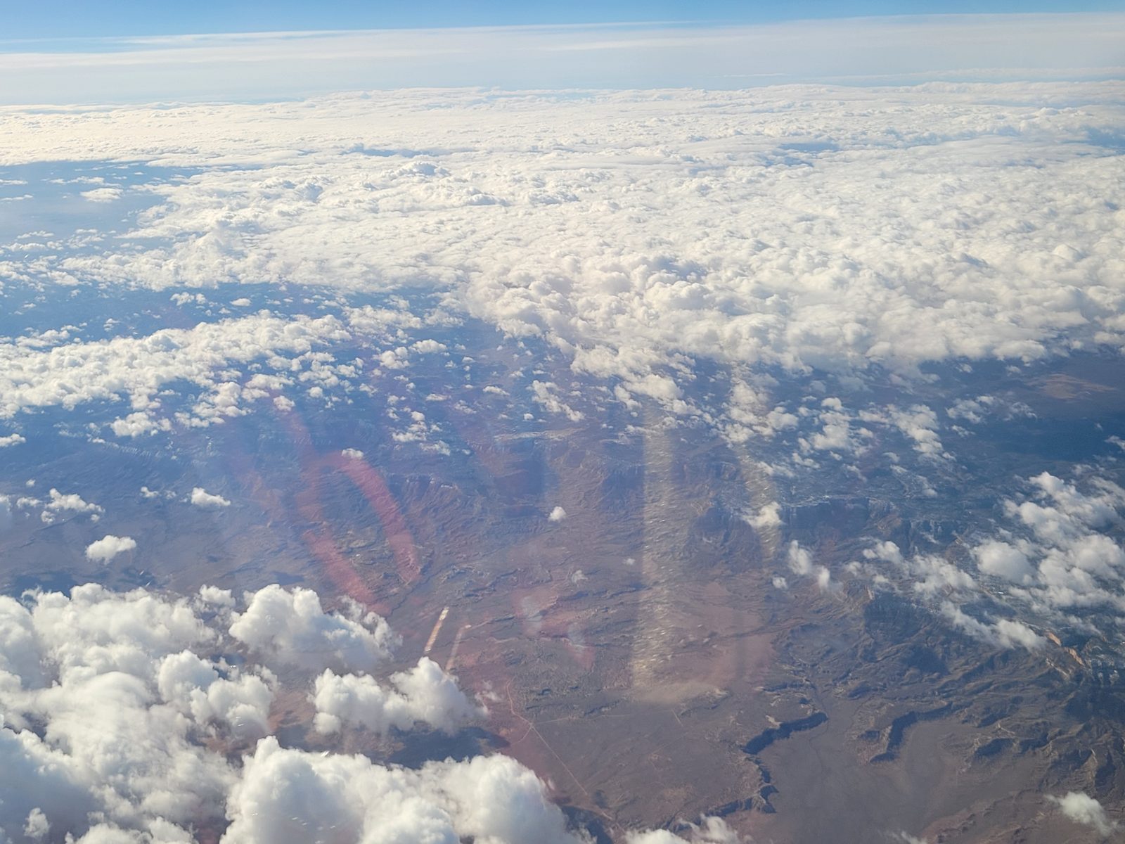 Red rock canyons through the clouds below