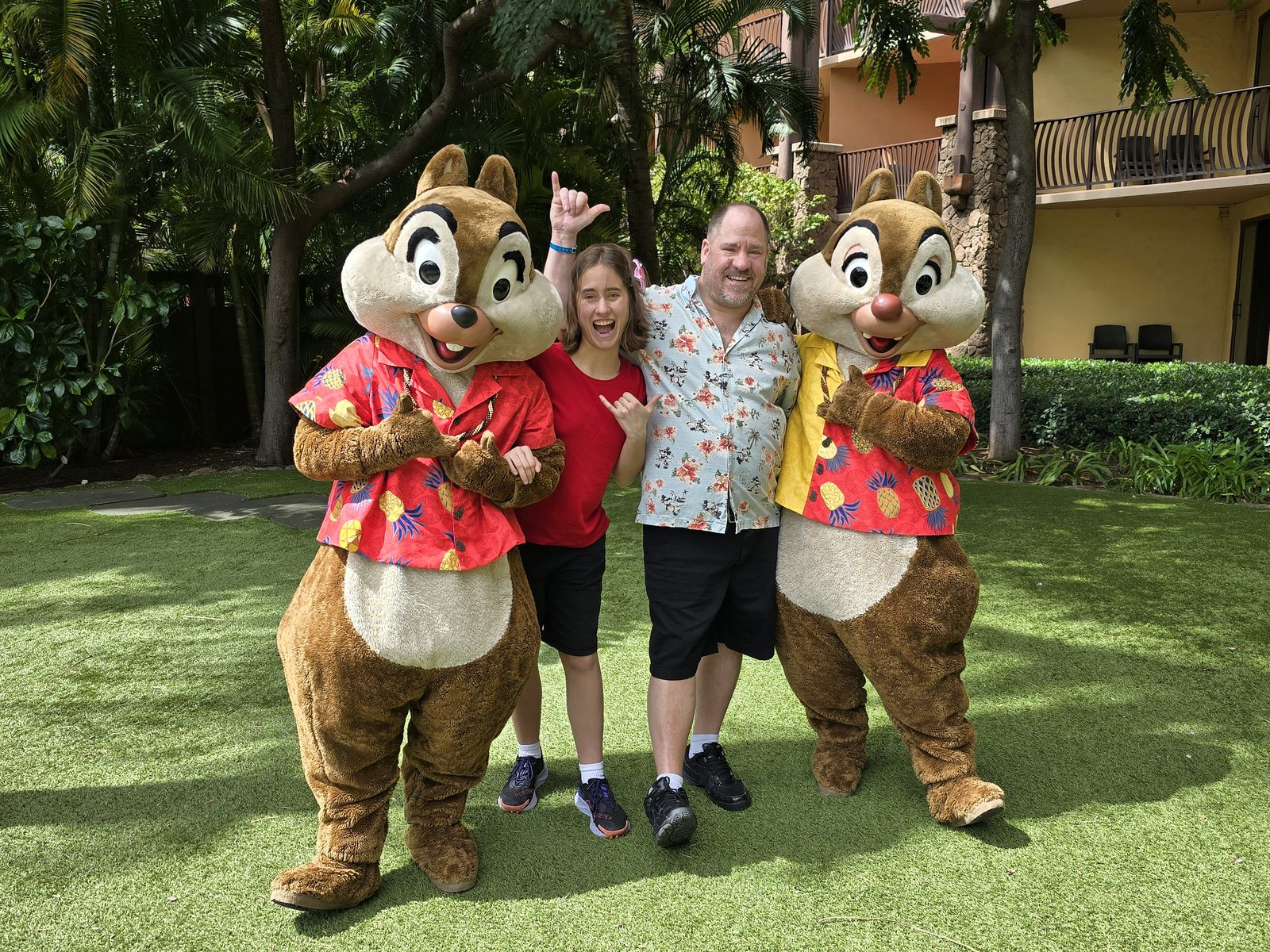 Lisa and Michael with Chip and Dale in their aloha shirts on the lawn at Aulani