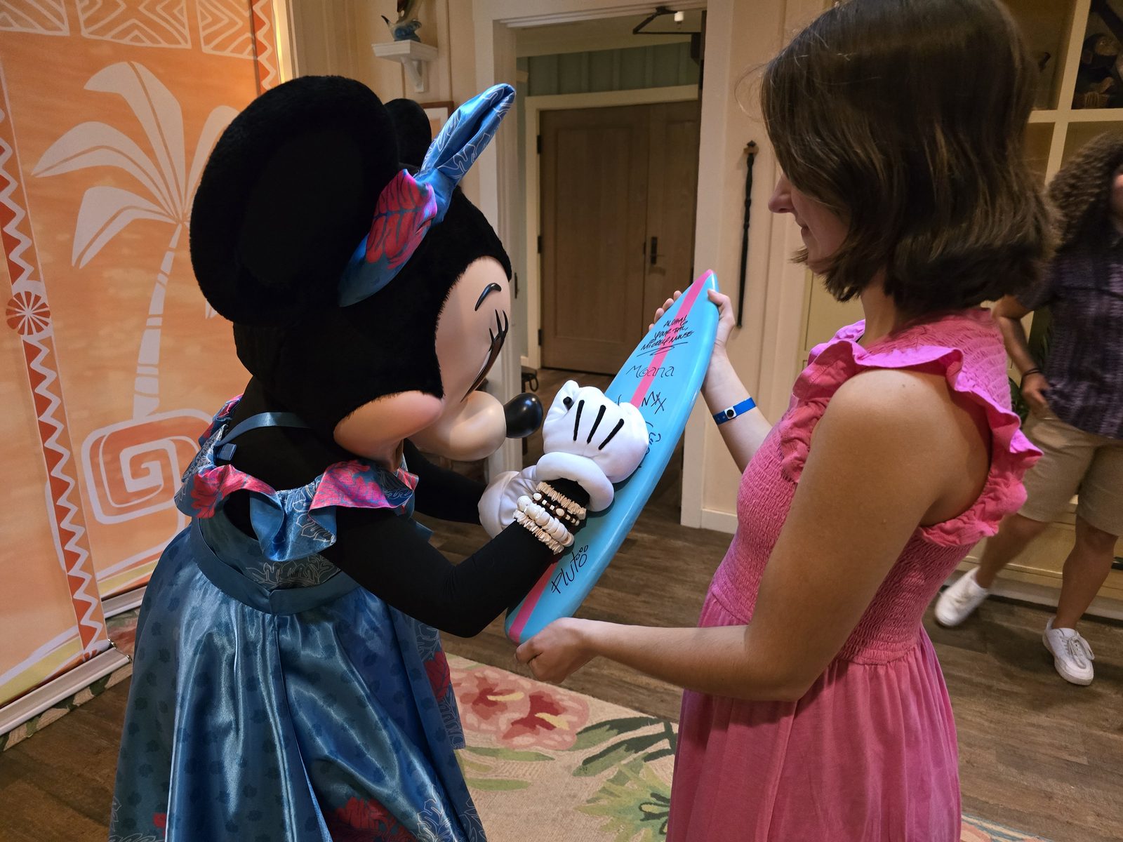Minnie Mouse in her blue evening dress signing Lisa's surfboard at Aulani