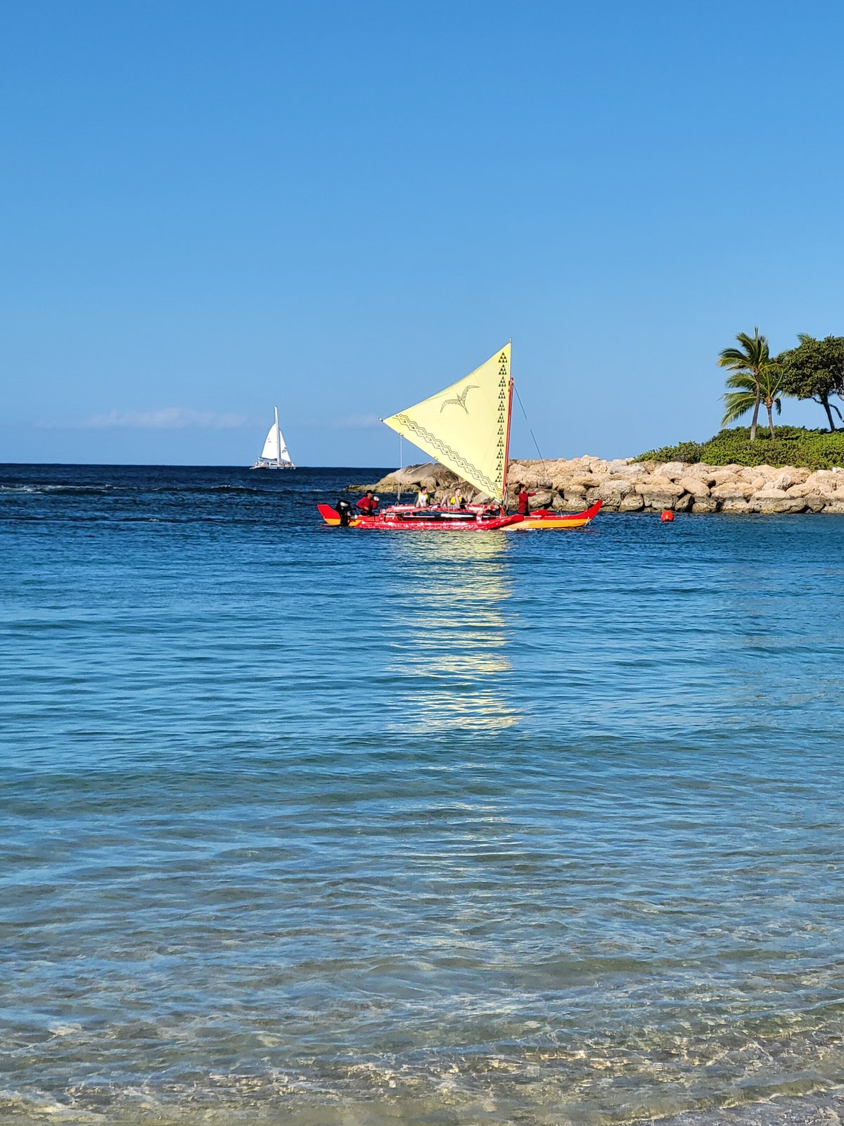 An outrigger canoe sailing past on the water