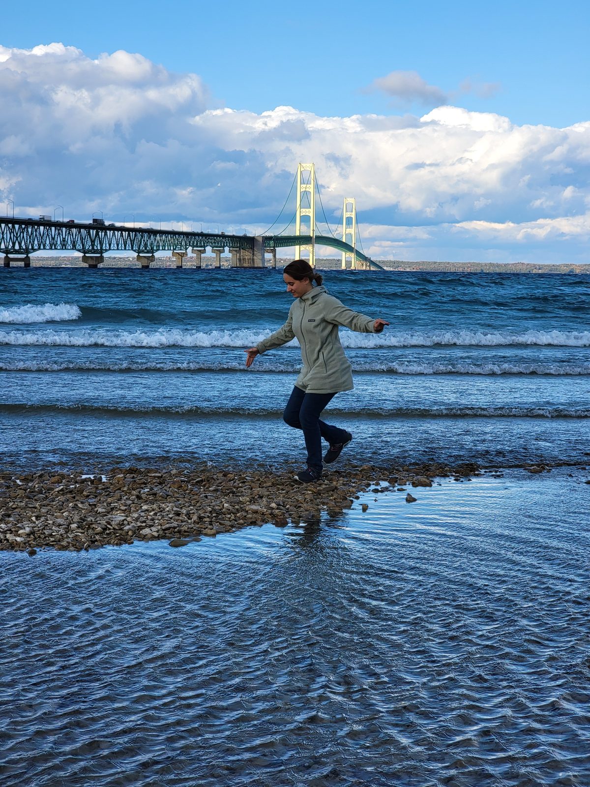 Lisa stepping through the shallows, the bridge behind her