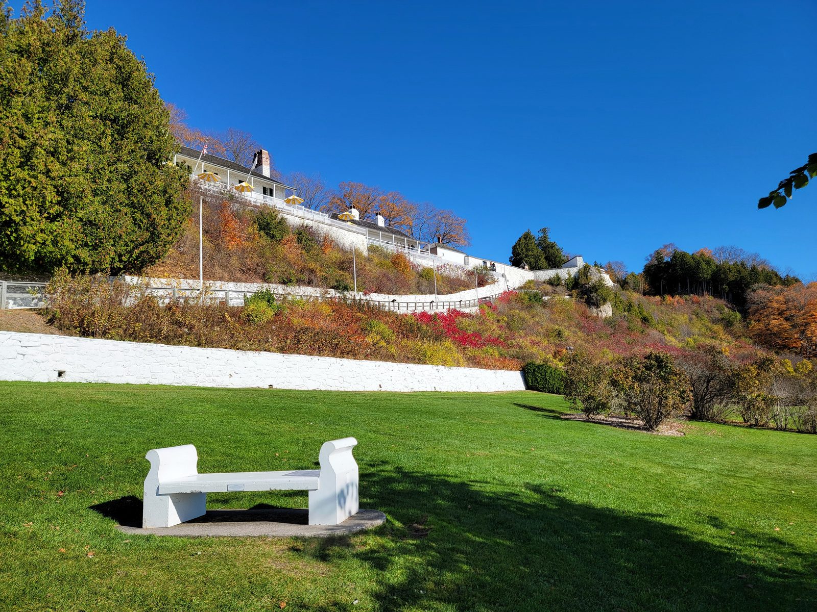 A white bench on the lawn below Fort Mackinac