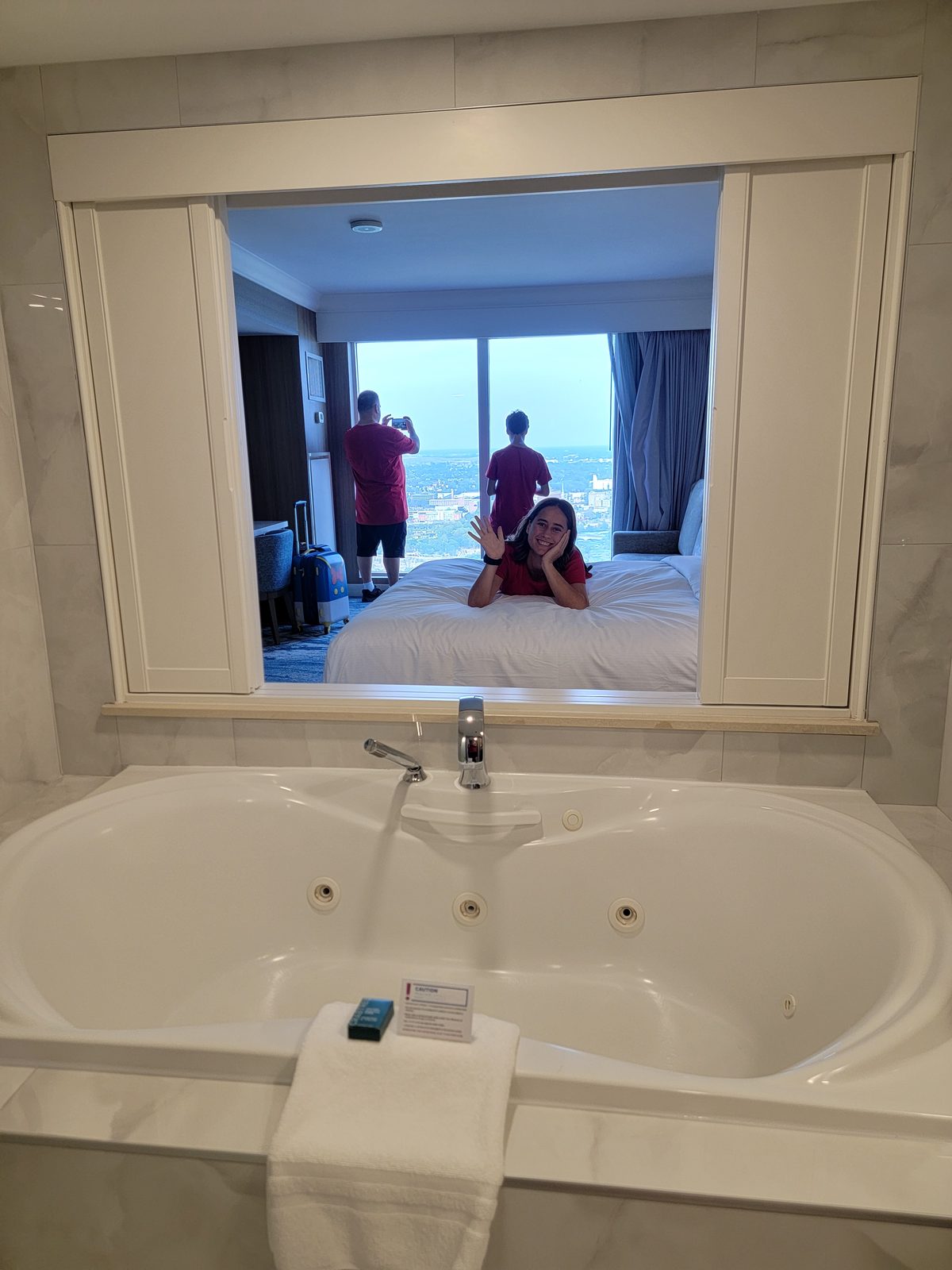 Lisa on the bed, seen through the jetted tub window