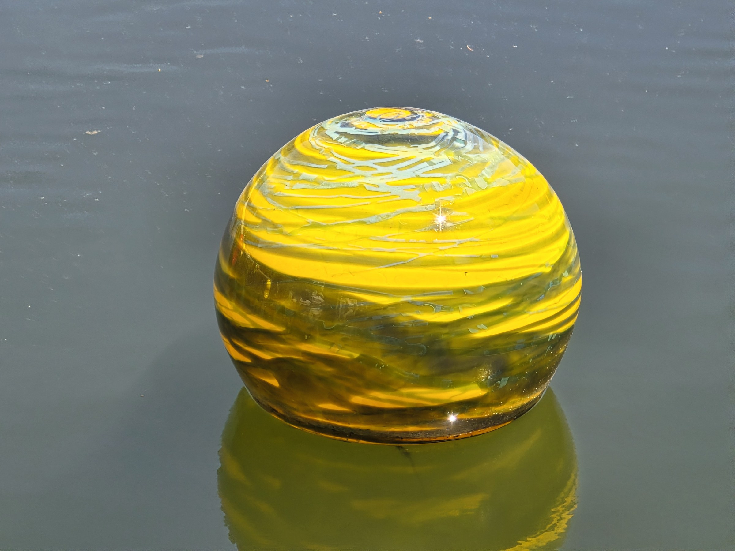 A yellow glass float on the pond
