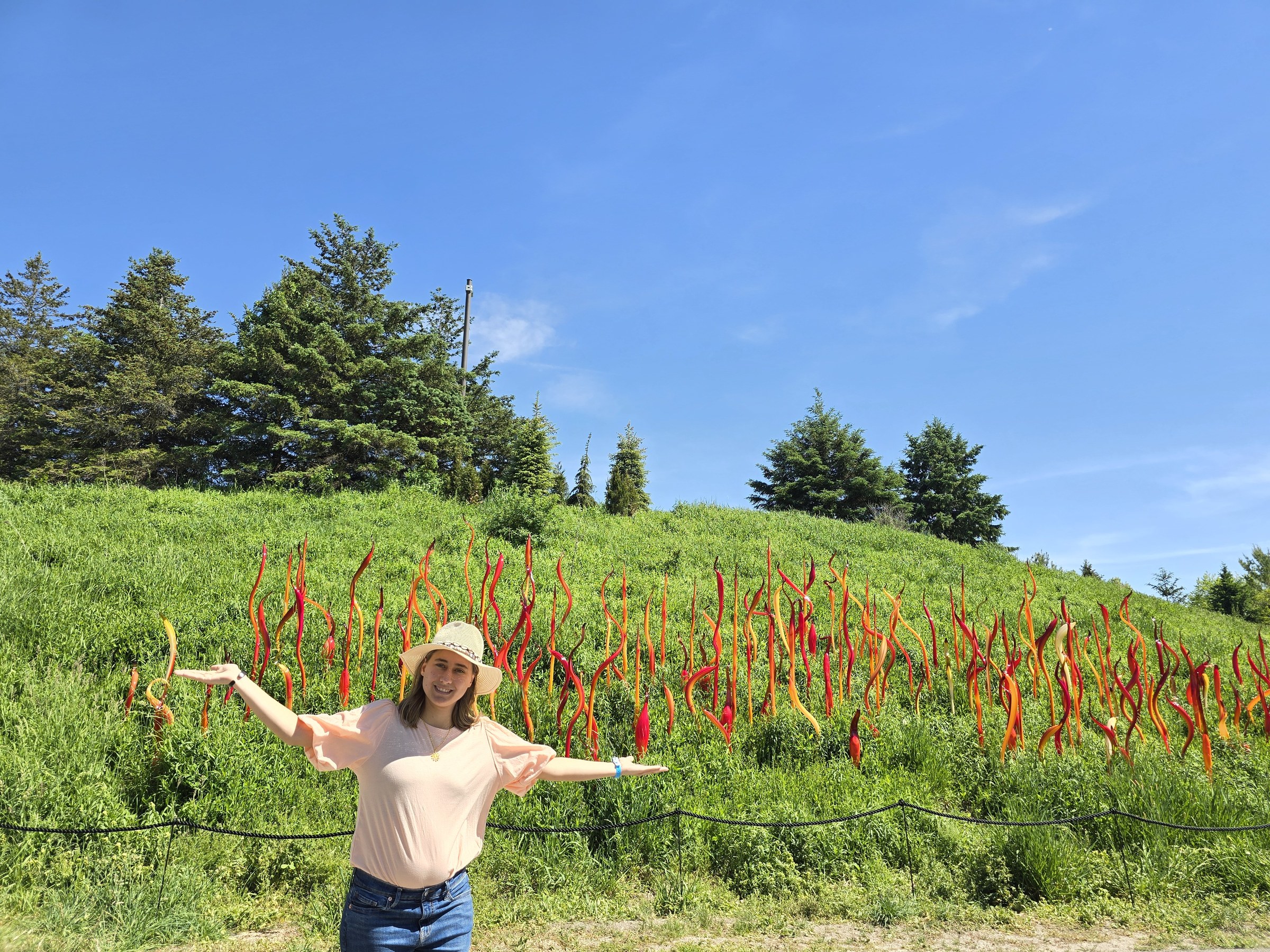 Lisa, arms wide, in front of the red glass reeds