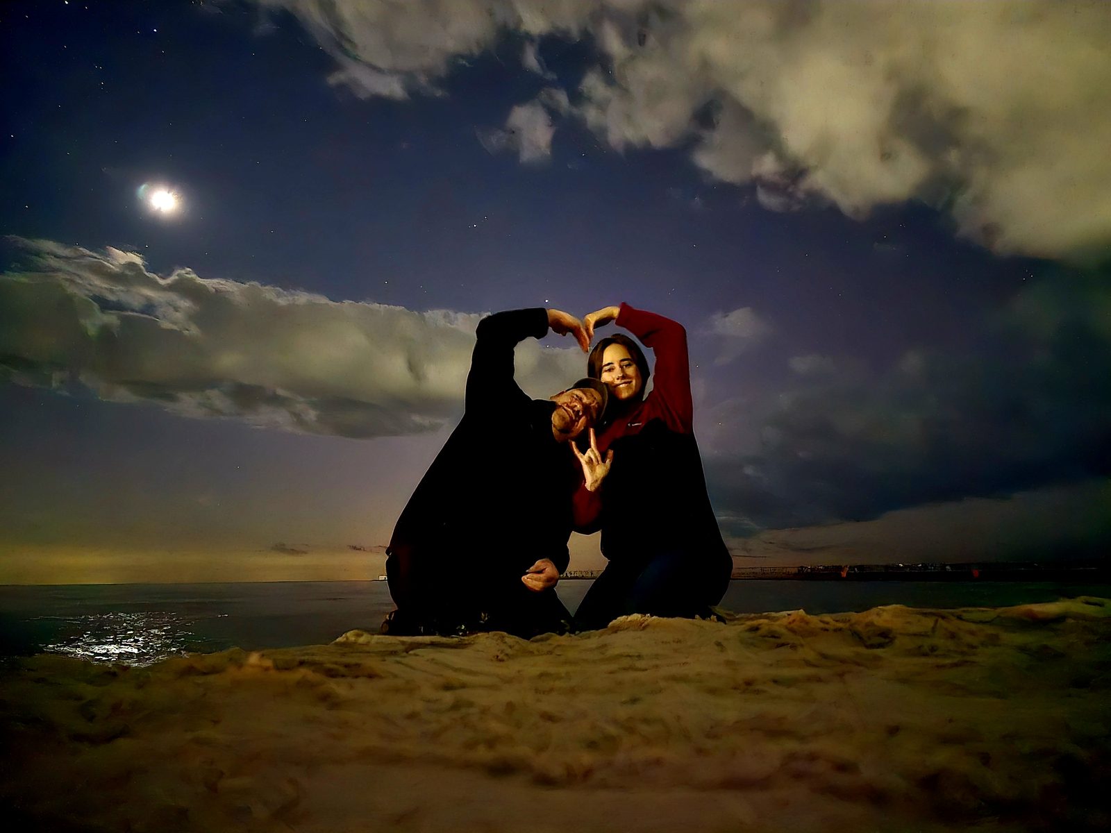 Lisa in a heart-shaped silhouette on the sand under the moon
